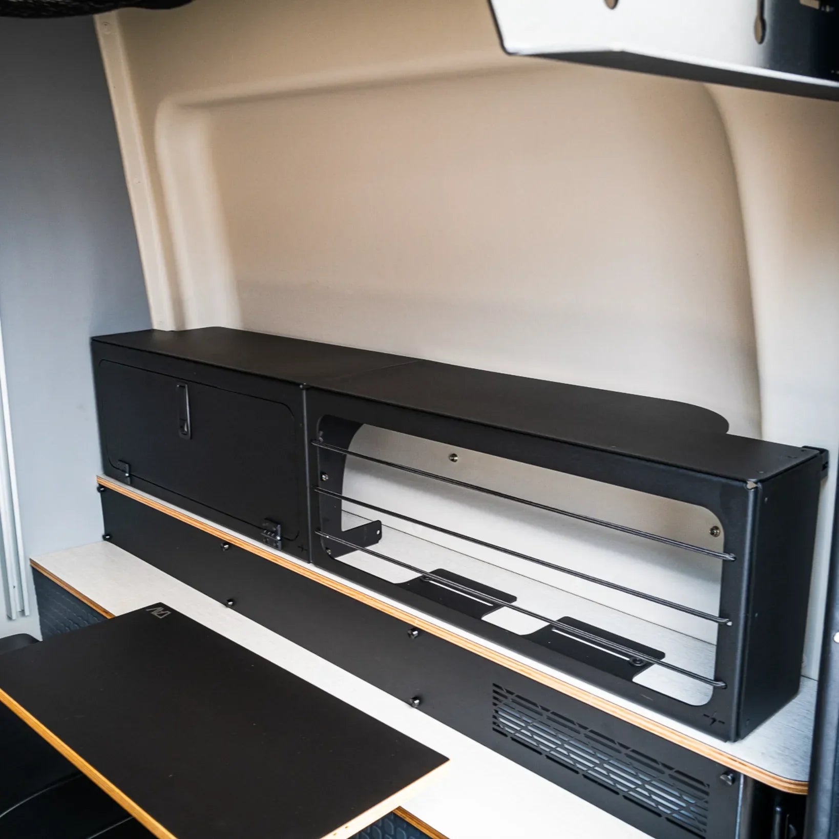 Bungee and lower storage box installed in a Winnebago Revel van interior above the bed area.