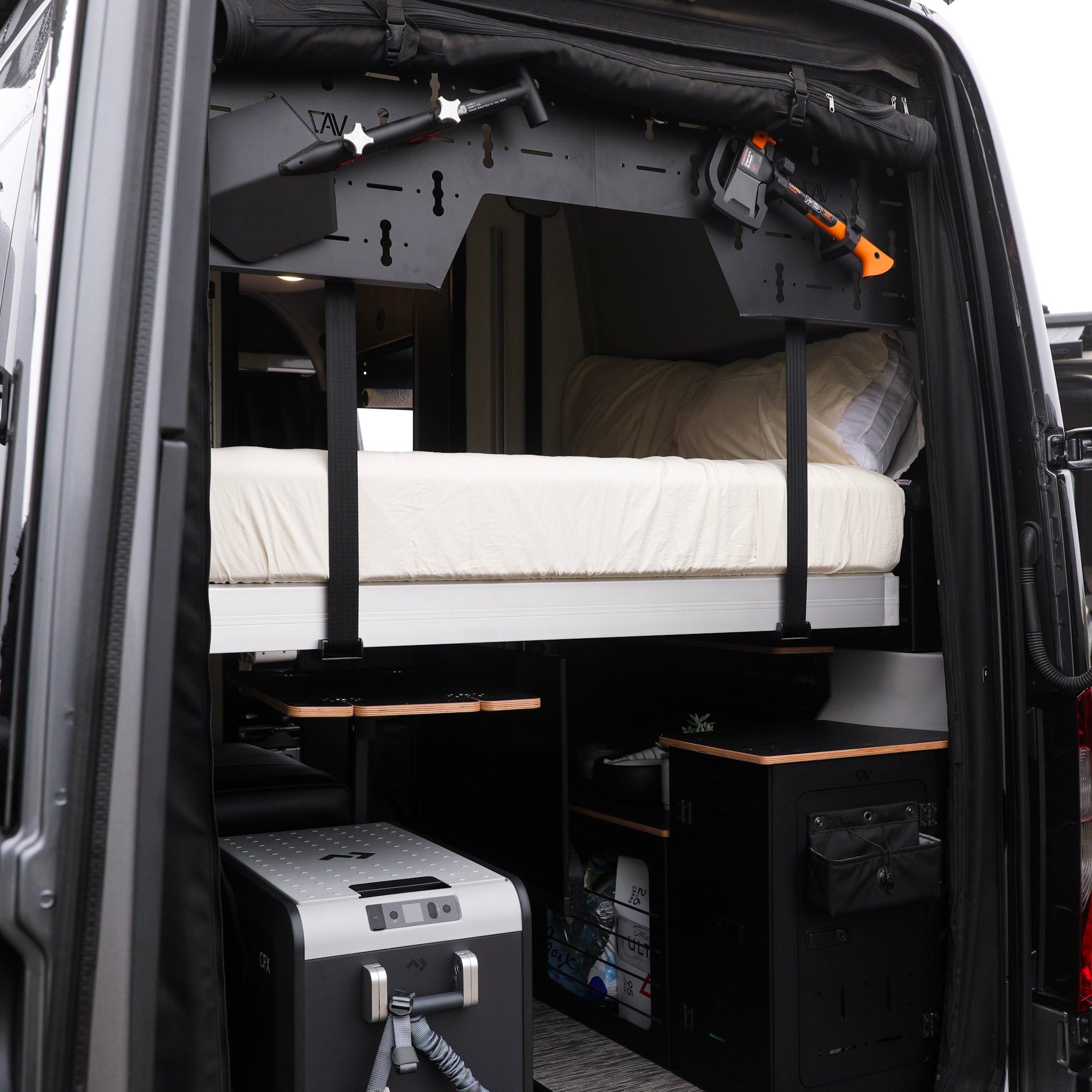 Rear view of a Terrain van with elevated Ultra Luxe mattress, gear storage, and compact kitchen setup.