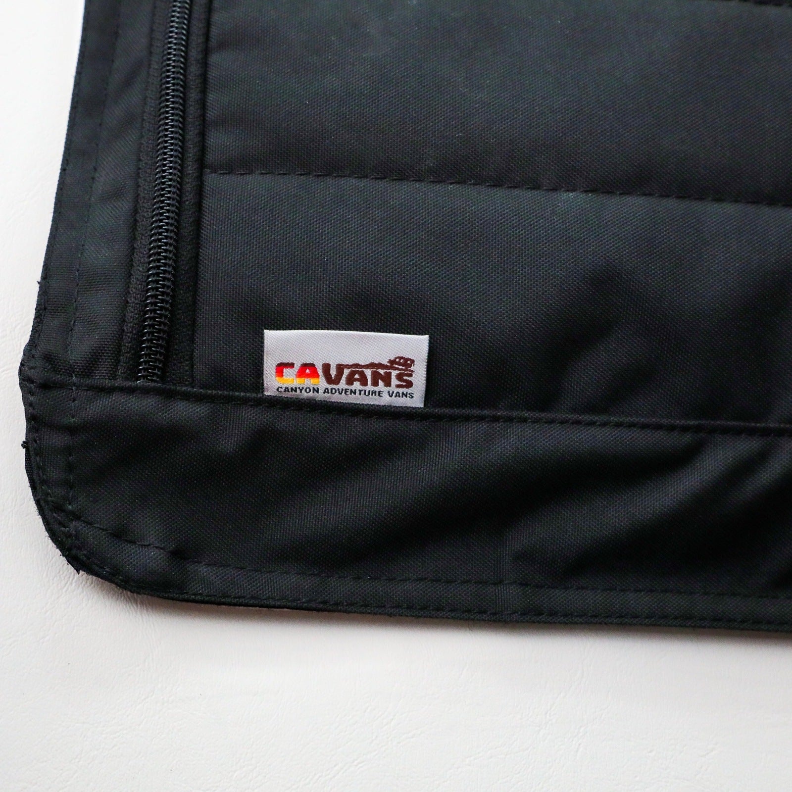 Close-up of black Clima-Shade panel with CAVANS logo tag on a white surface