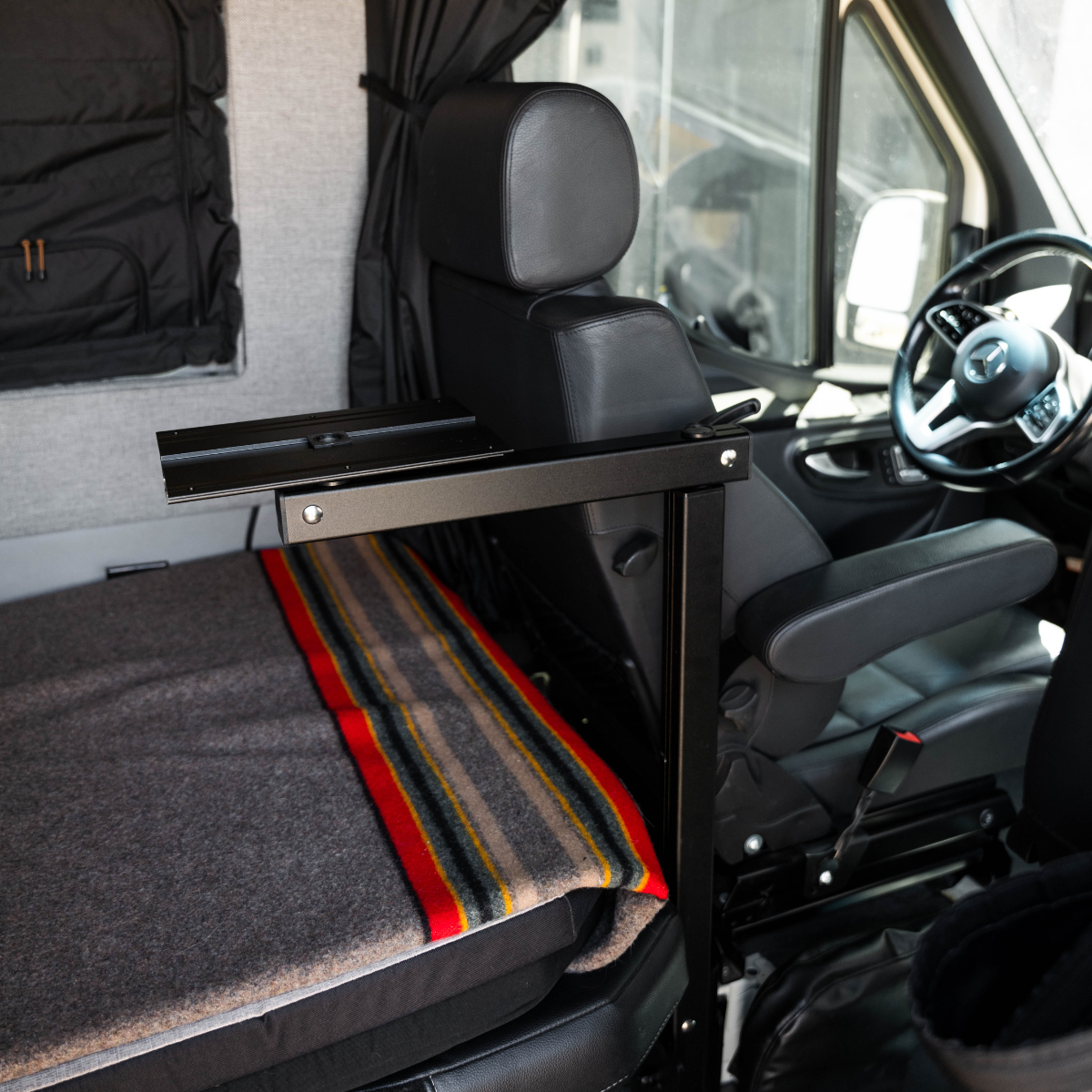 Canyon Table Leg System installed beside van seat with folded blanket on bench.