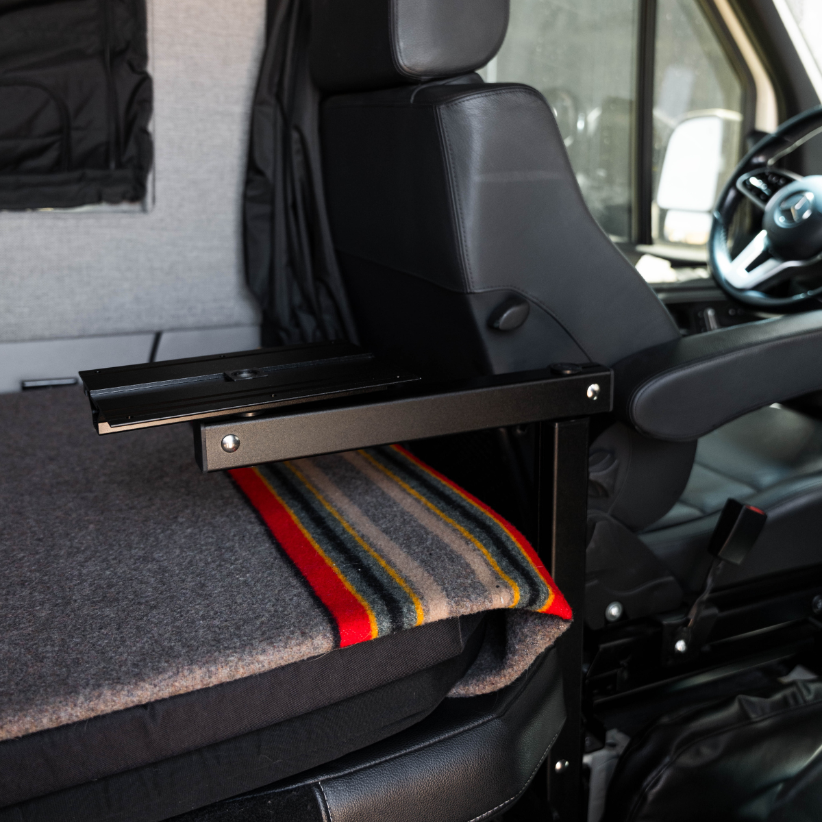 Canyon Table Leg System by GH1 mounted beside van seat with folded bed platform and blanket.