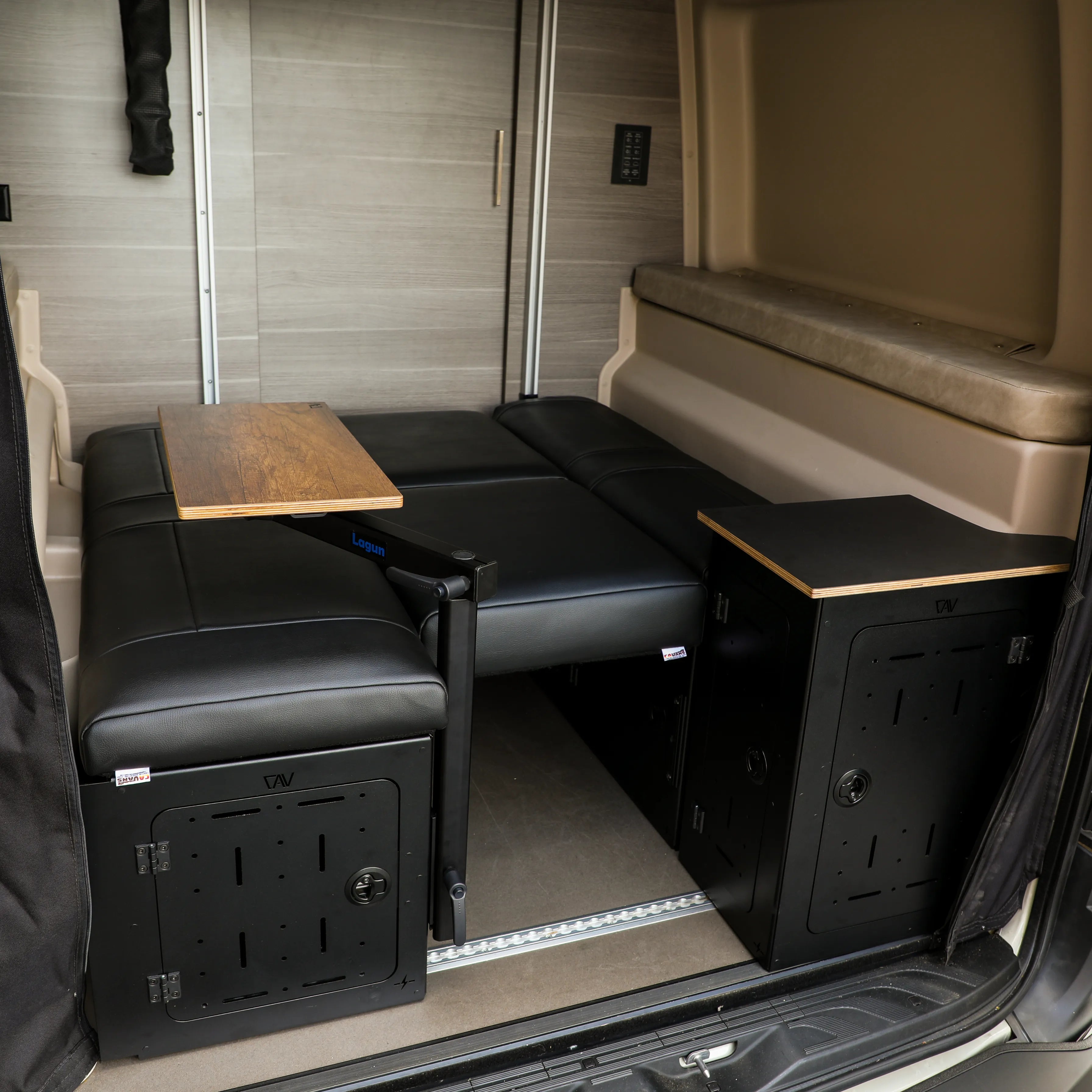 Revel day bed cushions mounted in van with foldable table between black storage units.