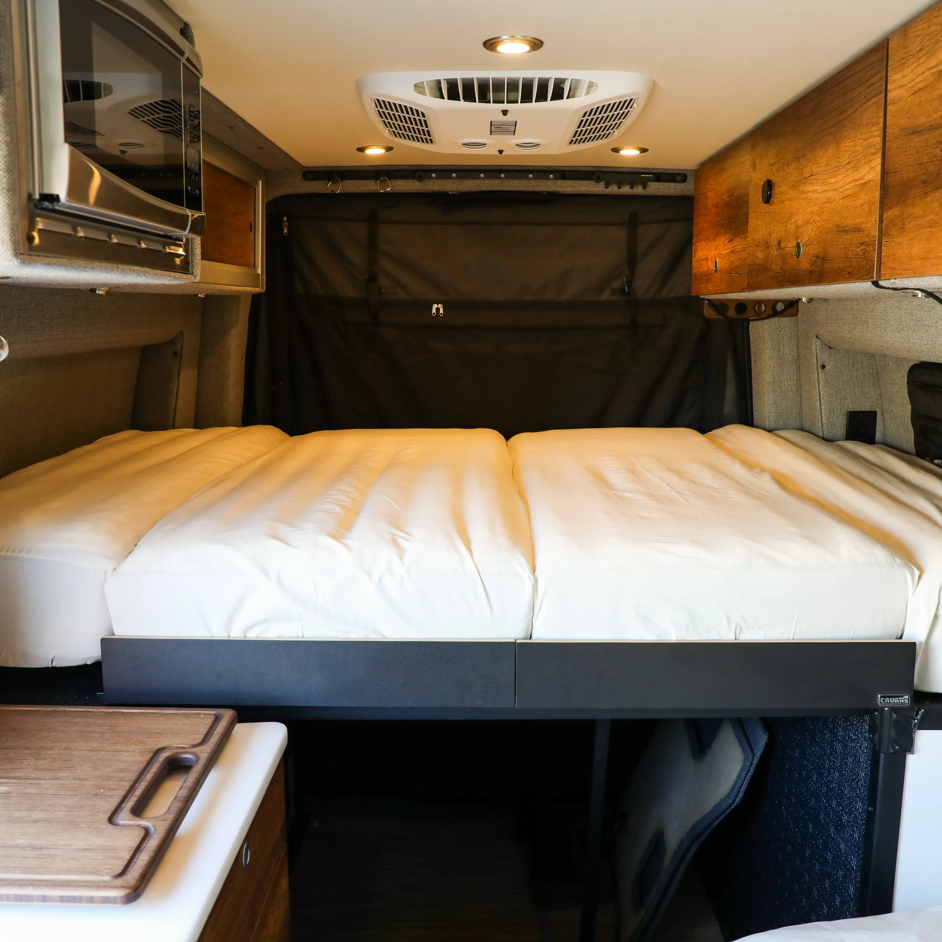 Storyteller Overland Dream Bundle bed setup in van interior with wood cabinetry and ceiling lights.