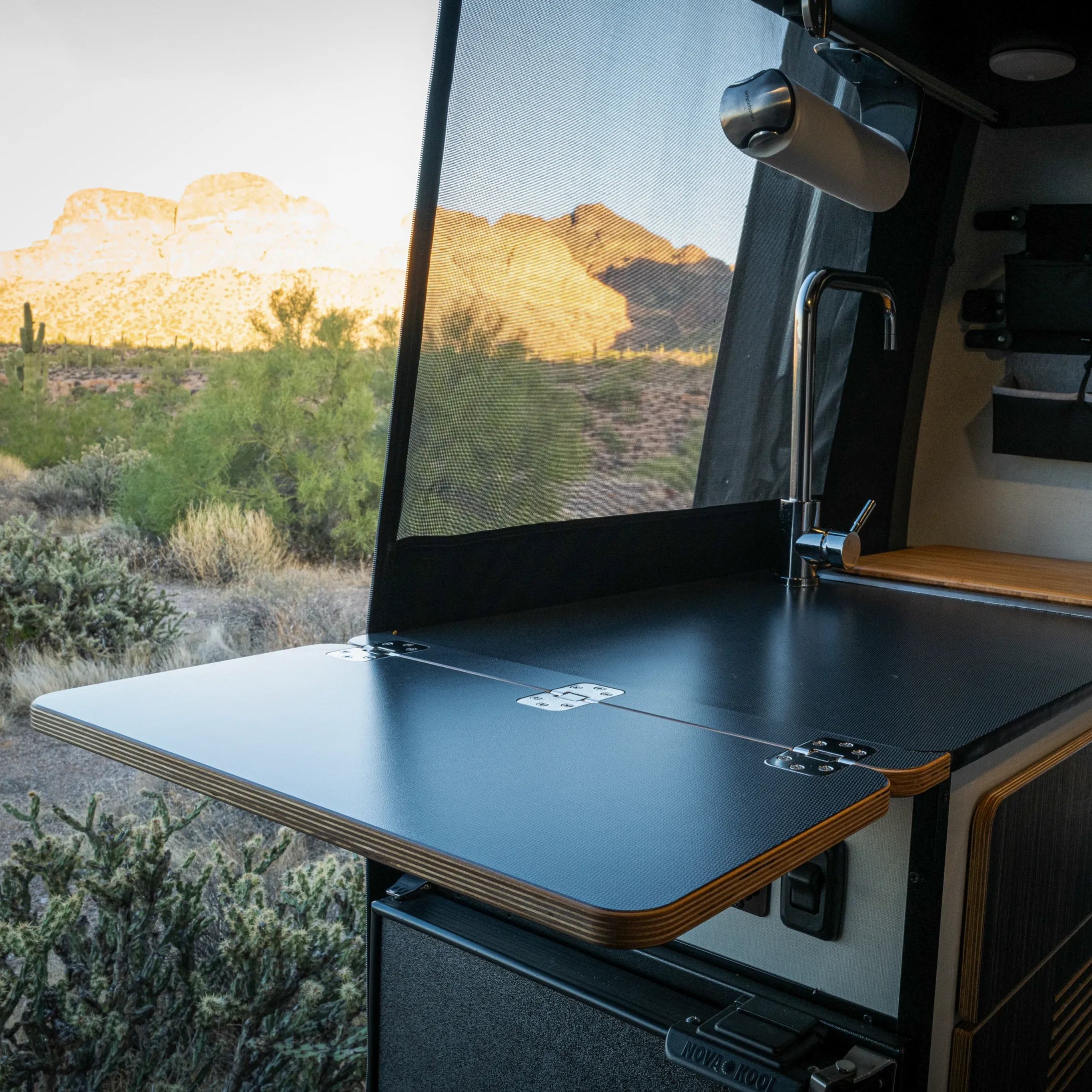 Revel folding countertop extension open inside van with desert view through the window.