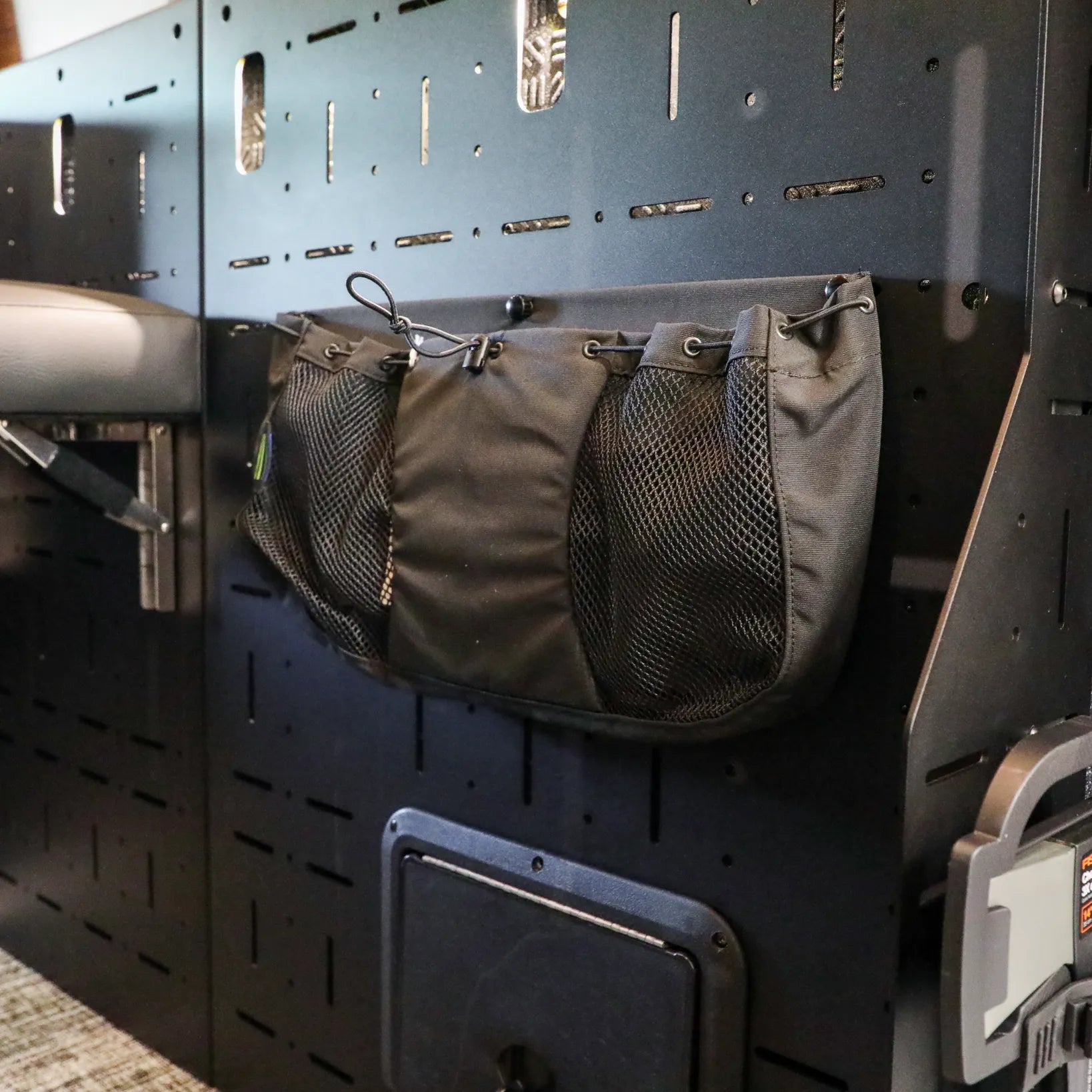 Passenger Gear Wall Pro by Storyteller Overland with mesh storage pouch mounted inside a van.