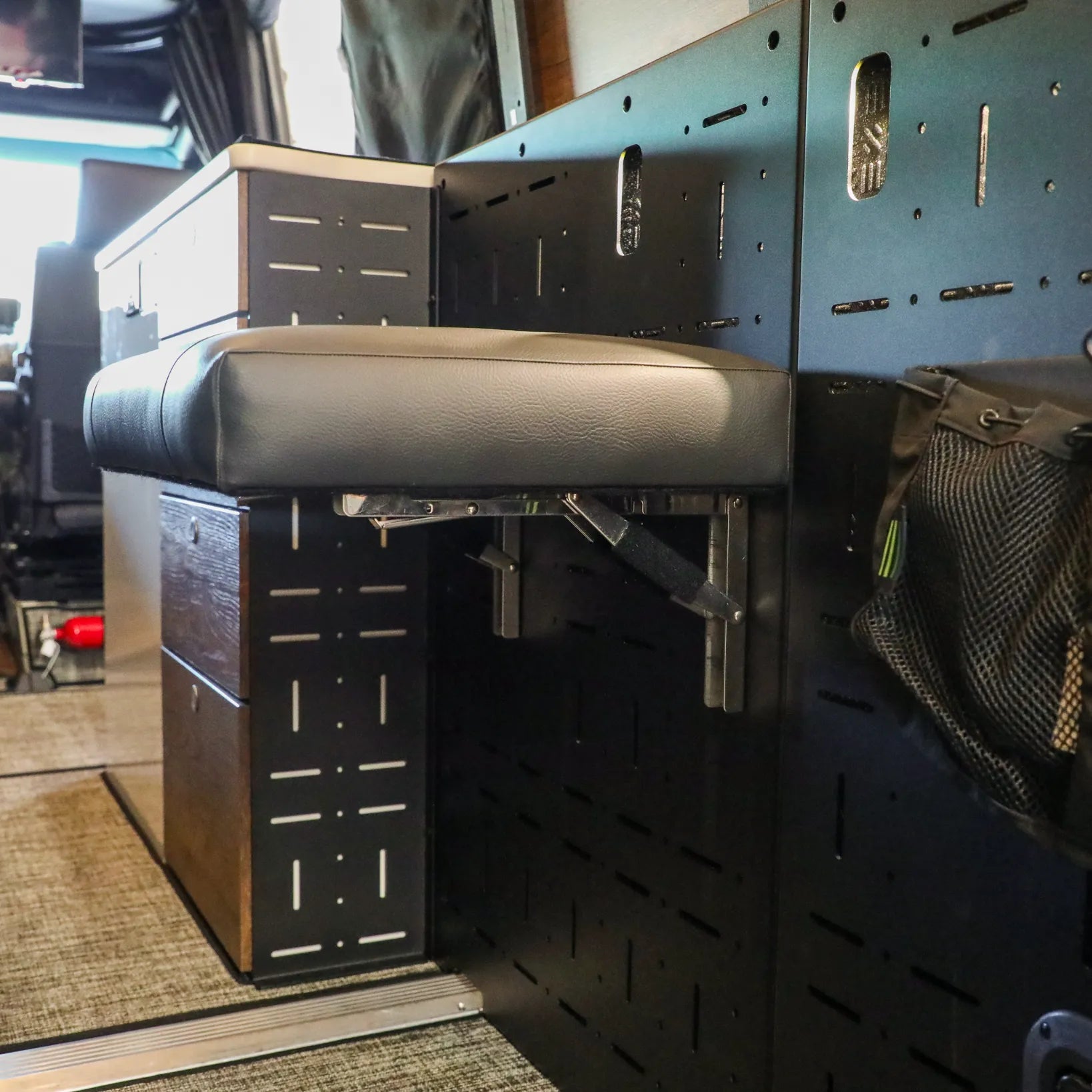 Passenger Gear Wall Pro by Storyteller Overland with fold-down seat in van interior