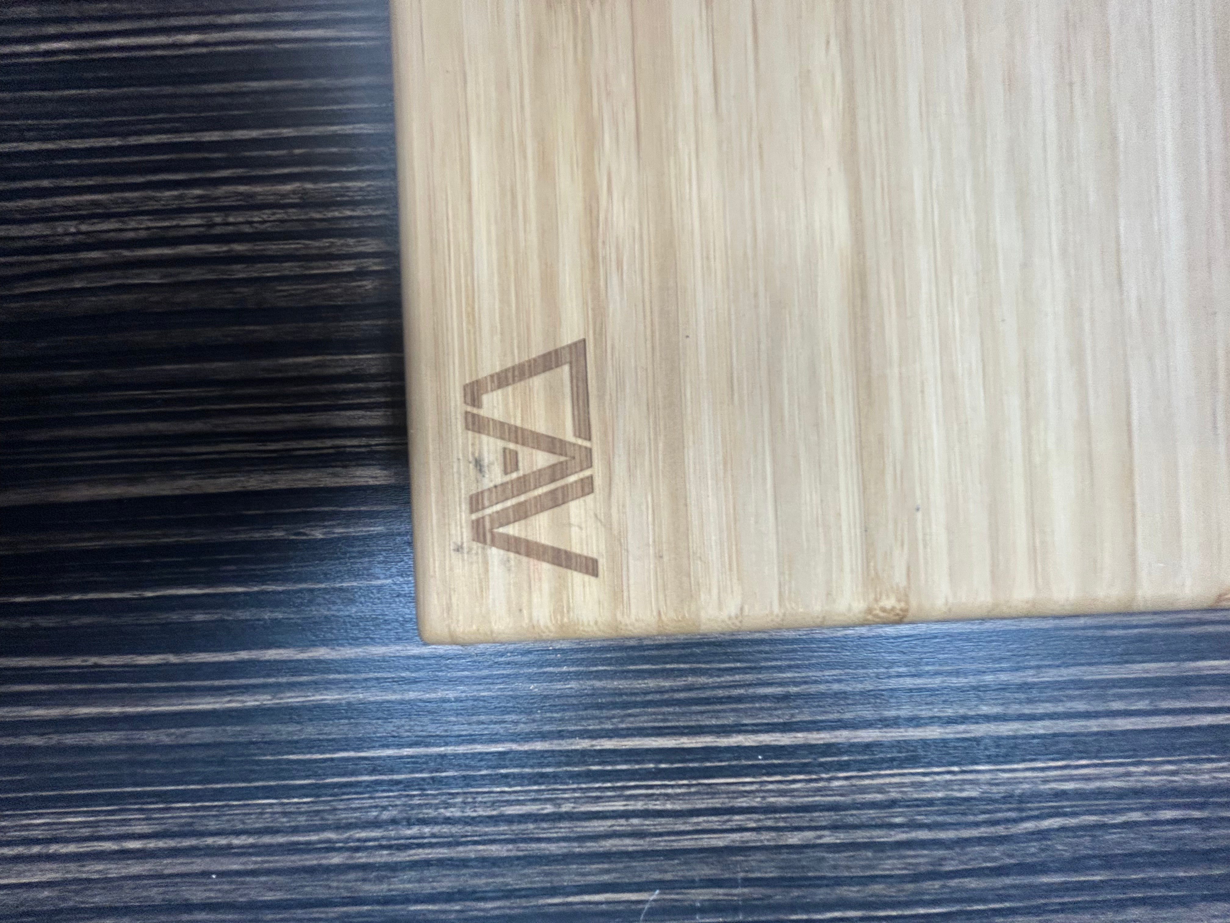 Close-up of the CAV logo engraved on a bamboo shelf surface.