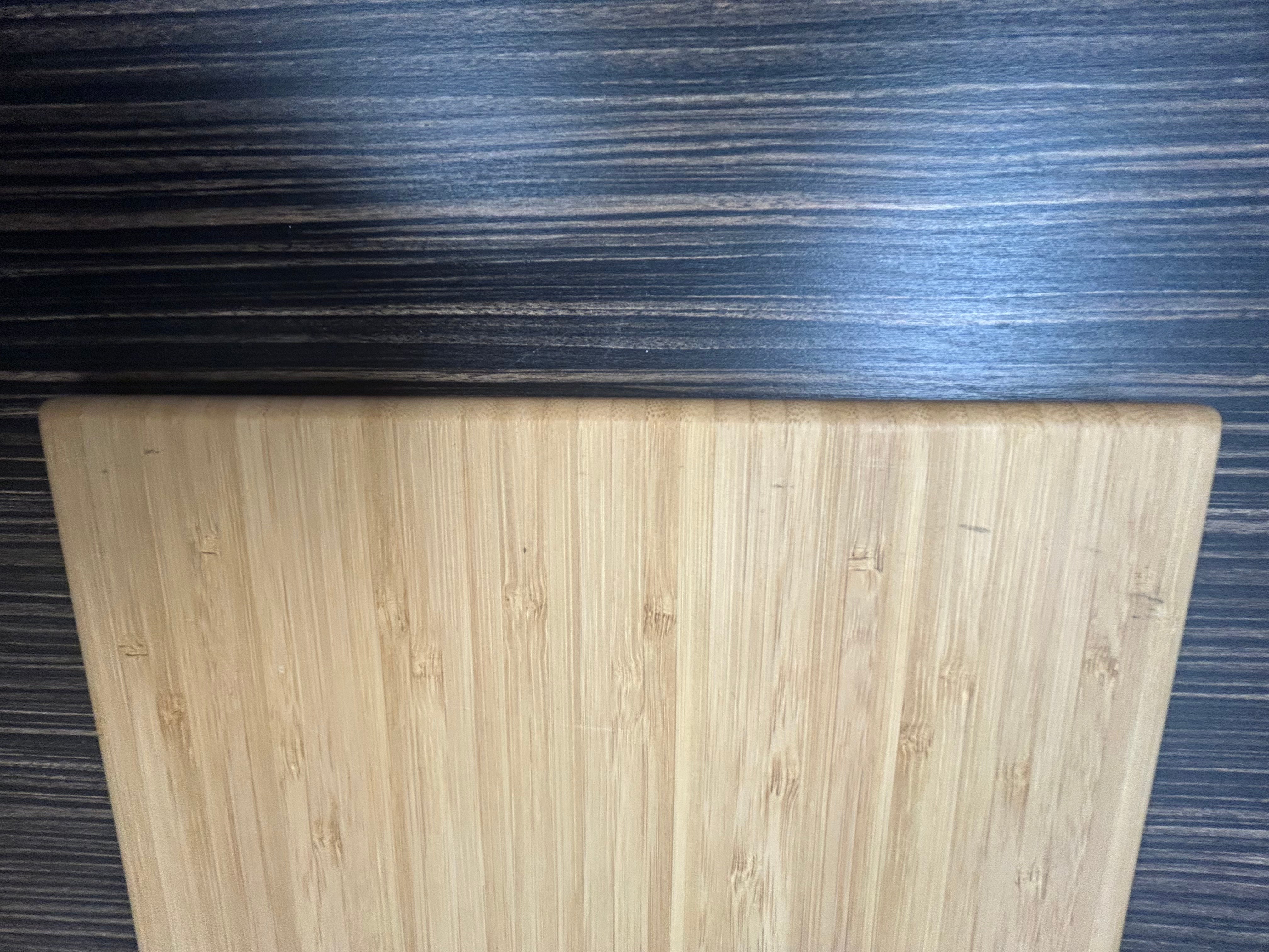 Close-up of the large Revel adjustable bamboo shelf against a wood-textured surface.