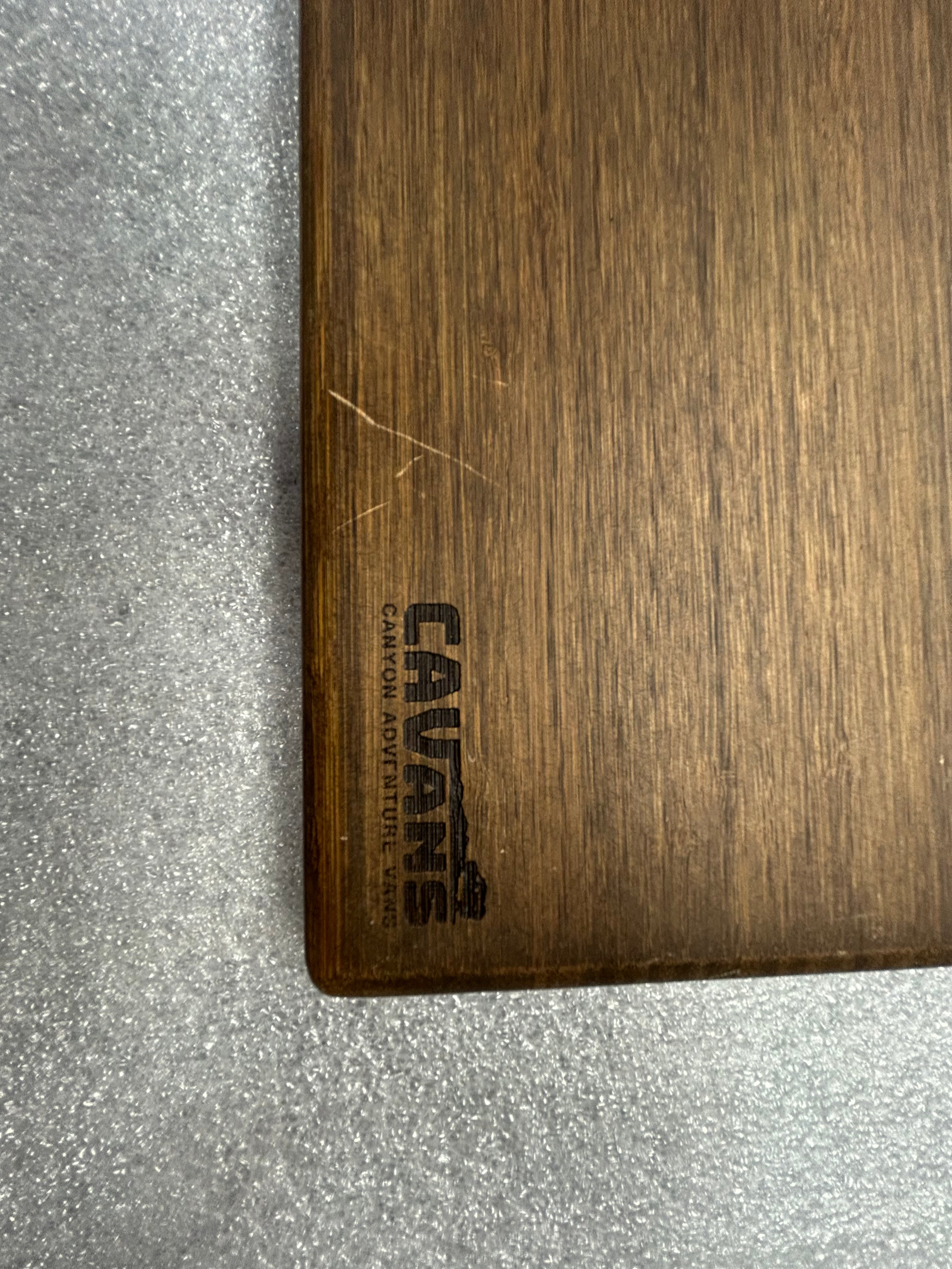 Corner of a CAVANS small universal tabletop with dark wood finish on textured surface.