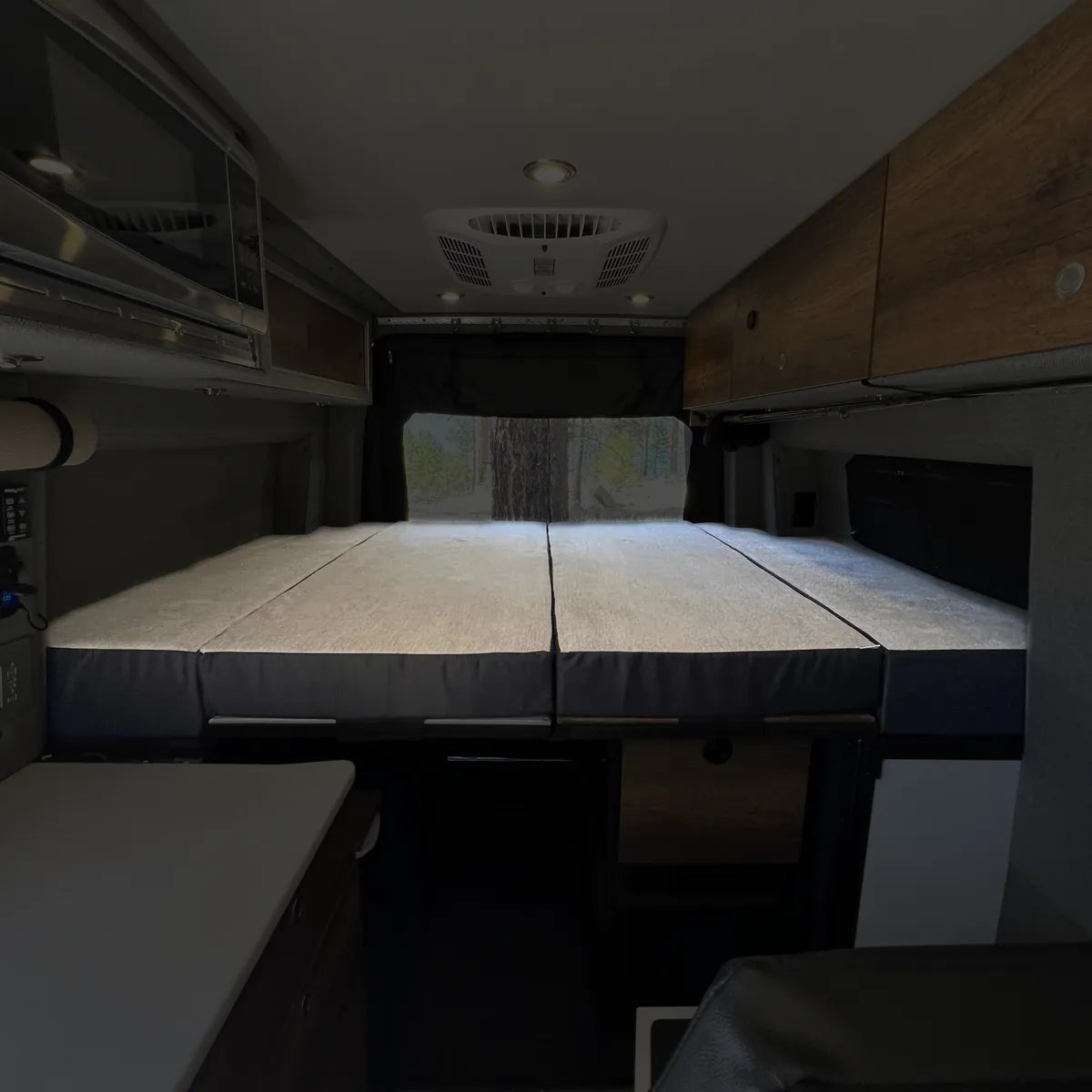 Luxe5 cooling memory foam mattress laid out in van interior with wood cabinets and ceiling fan.