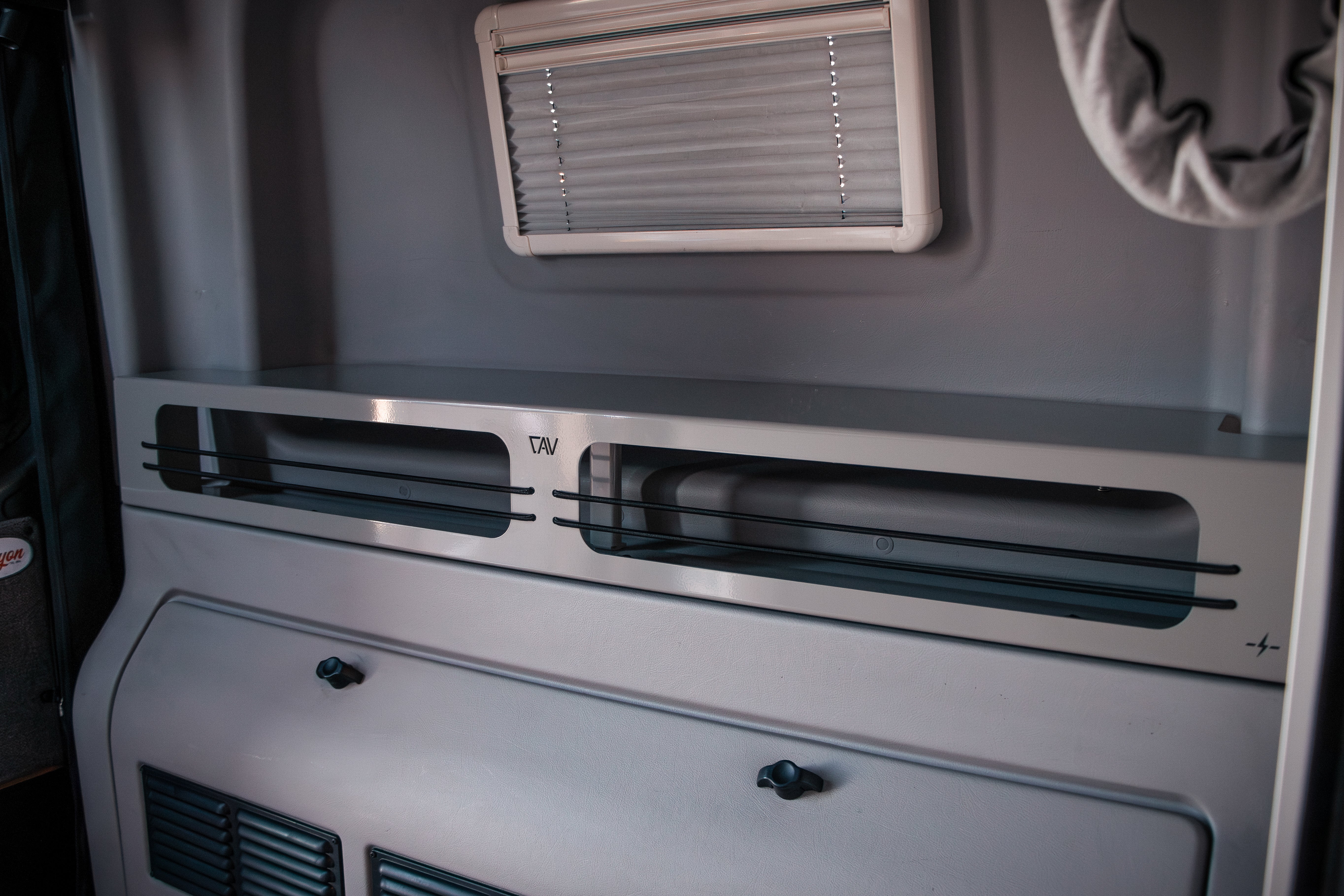 Close-up of grey Revel 6-inch bed risers installed in a van interior.