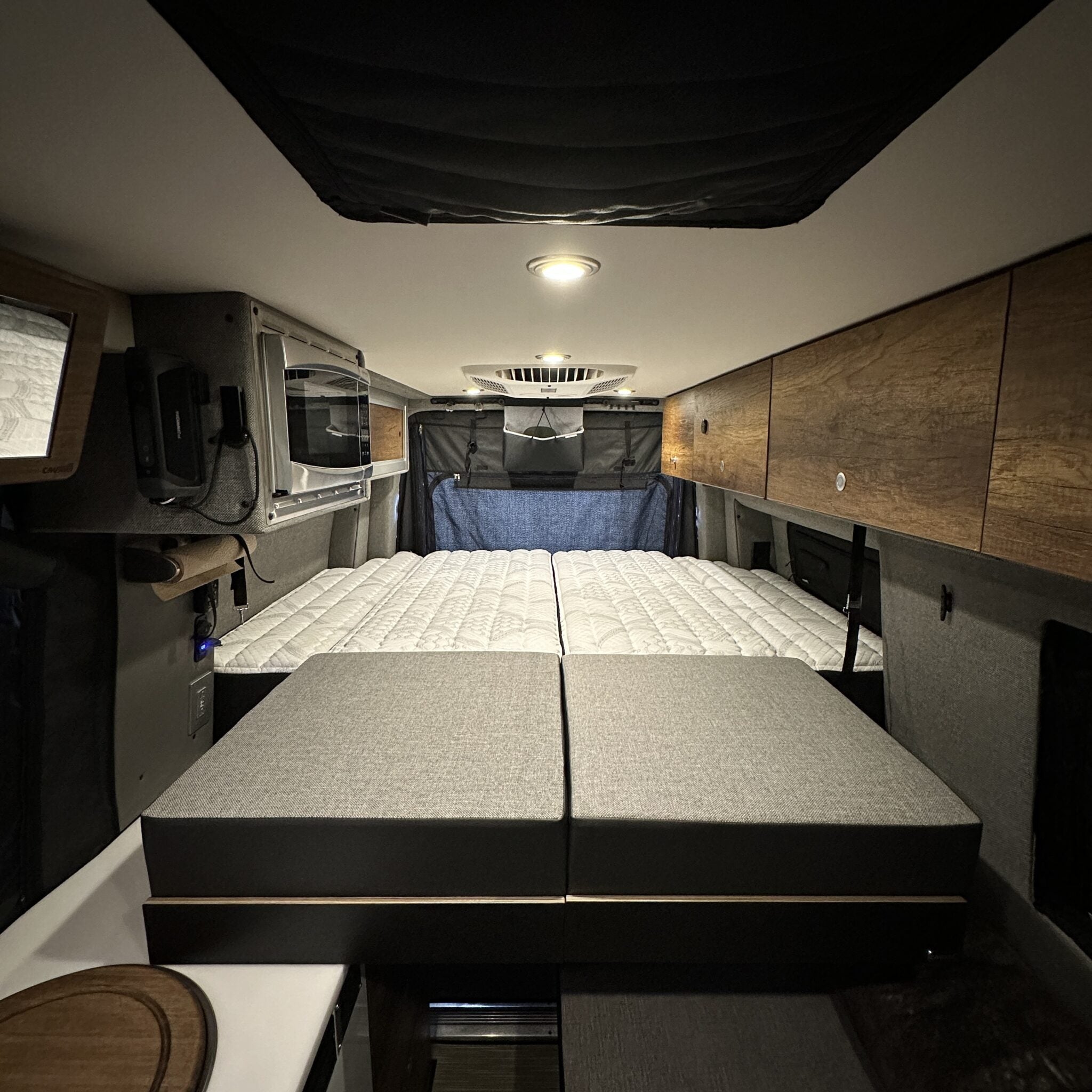 Storyteller Murphy bed system with slide-out extensions set up in van interior with overhead storage.