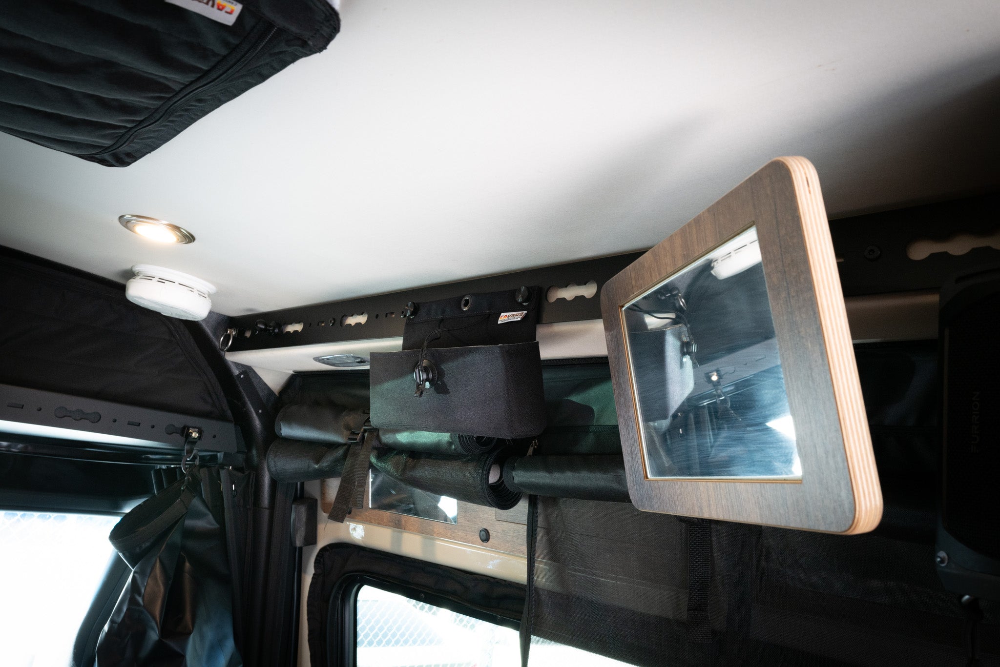 L-Track Pro rail system installed on van ceiling with mounted bag and fold-out mirror panel.