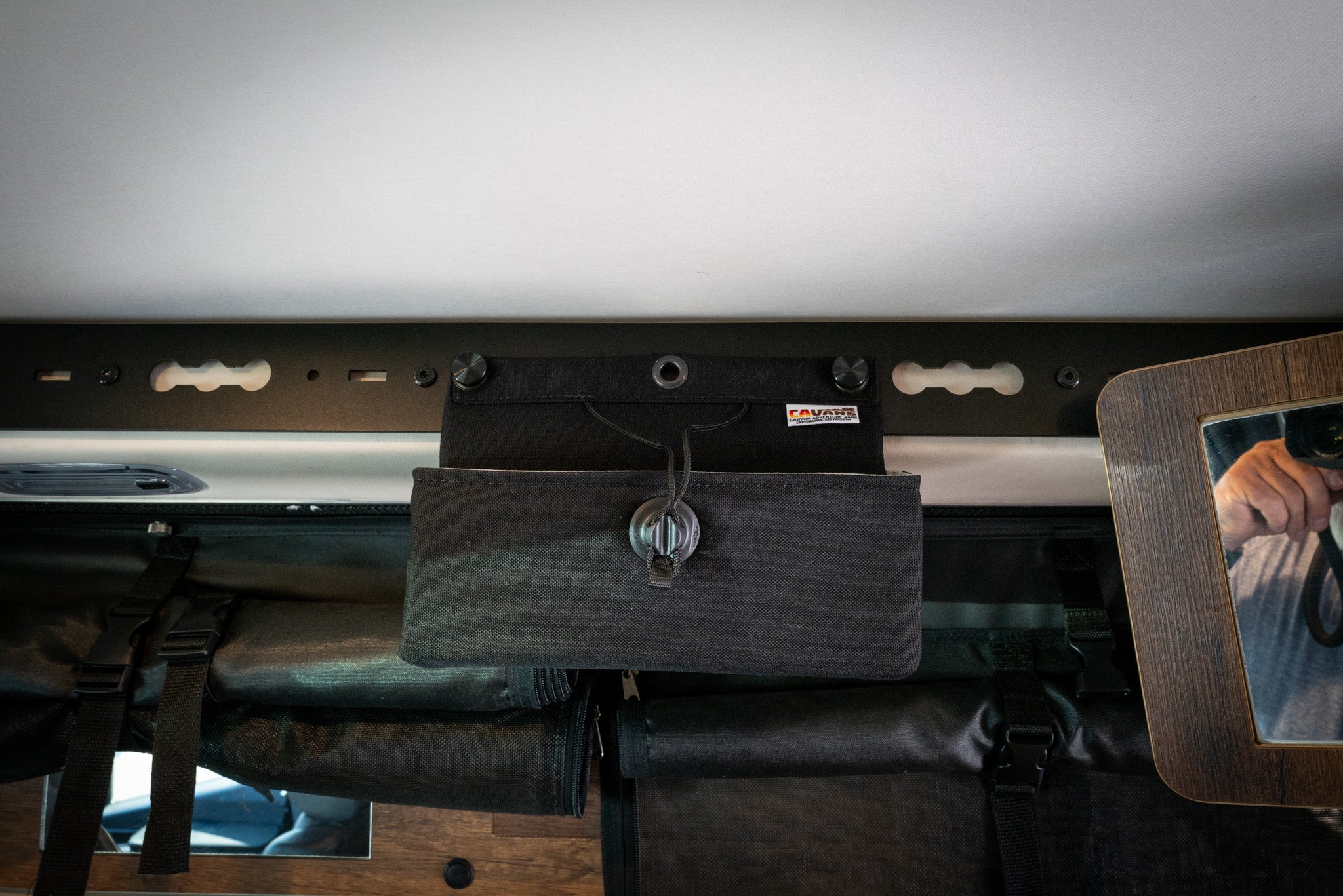 L-Track Pro mounted above sliding door in a Storyteller Overland van interior with storage pouch attached