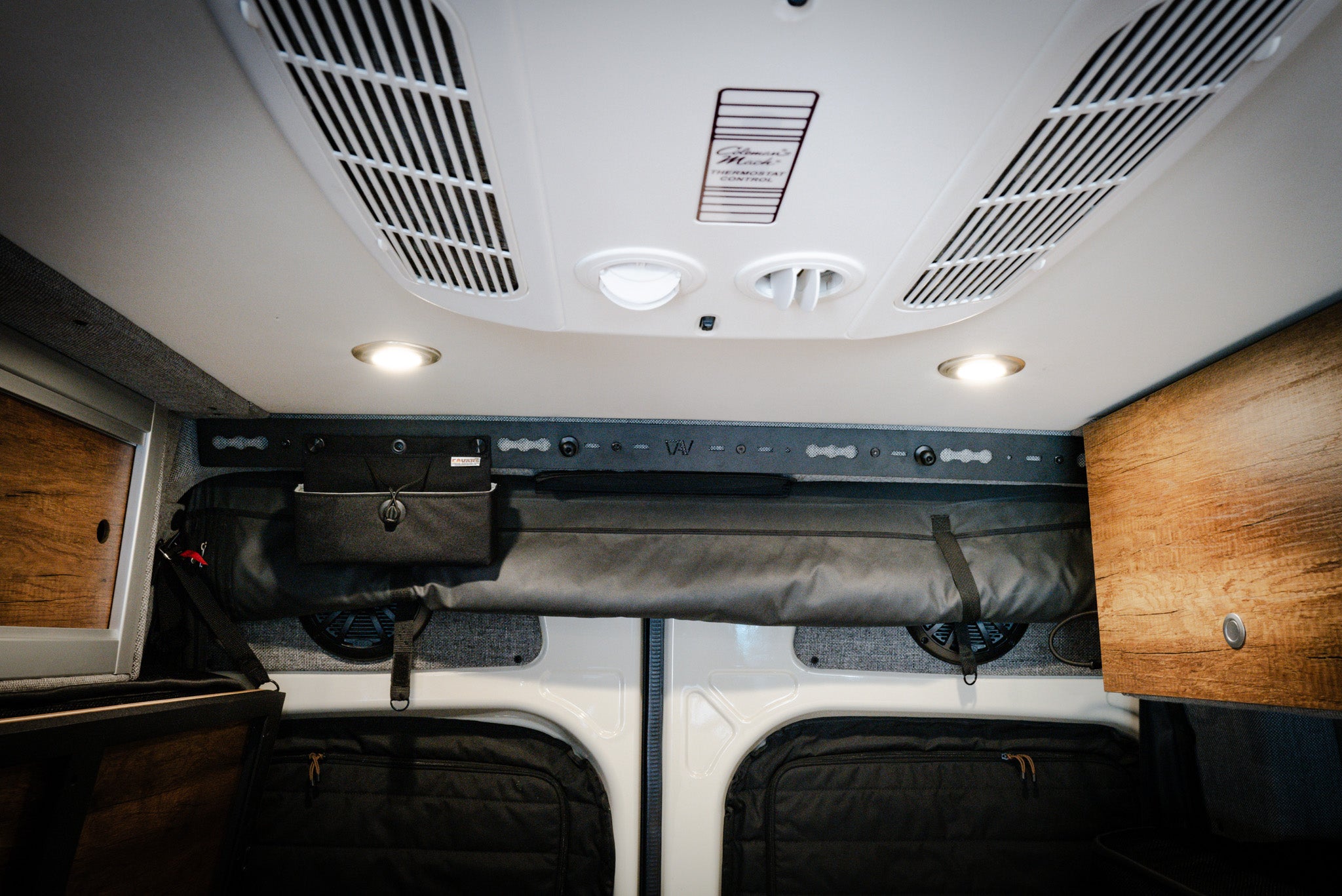 L-Track PRO mounted above rear doors inside a Storyteller Overland van with wood cabinets and gear storage.