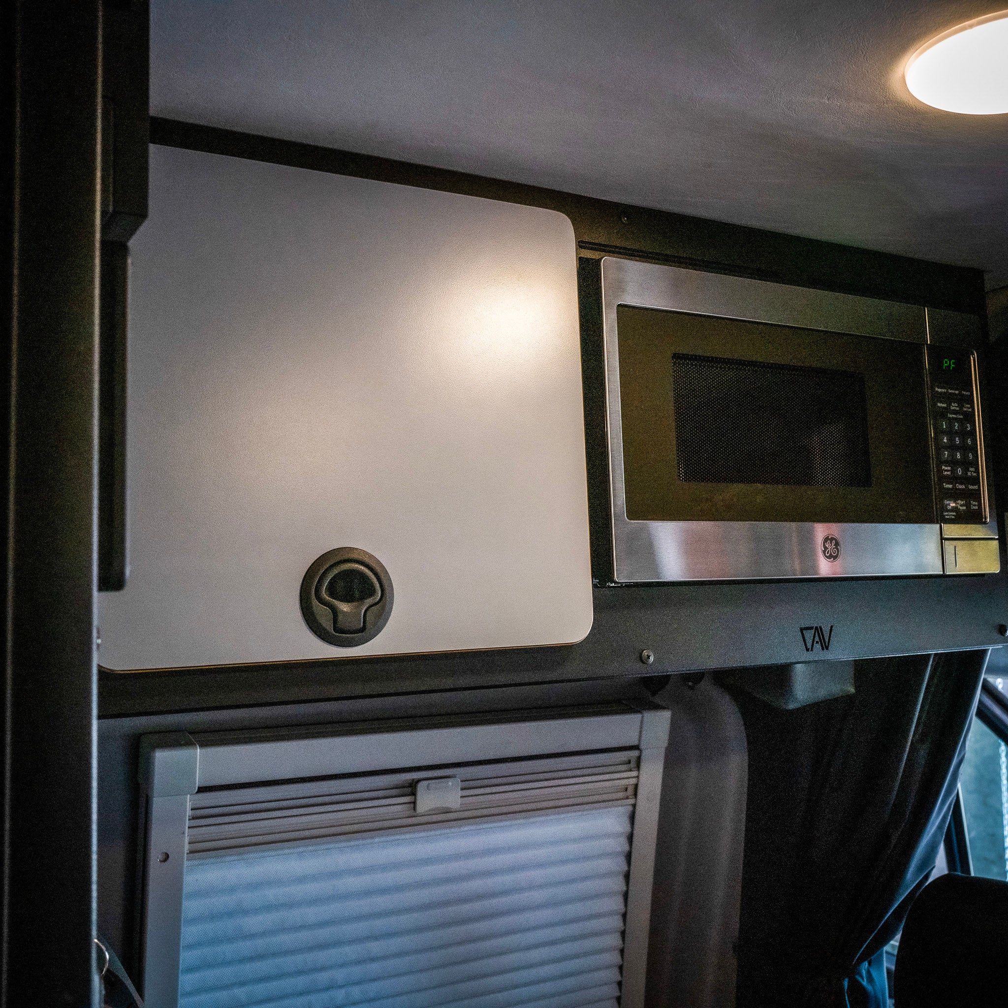 Revel overhead cabinet kit with built-in GE microwave inside a van interior.