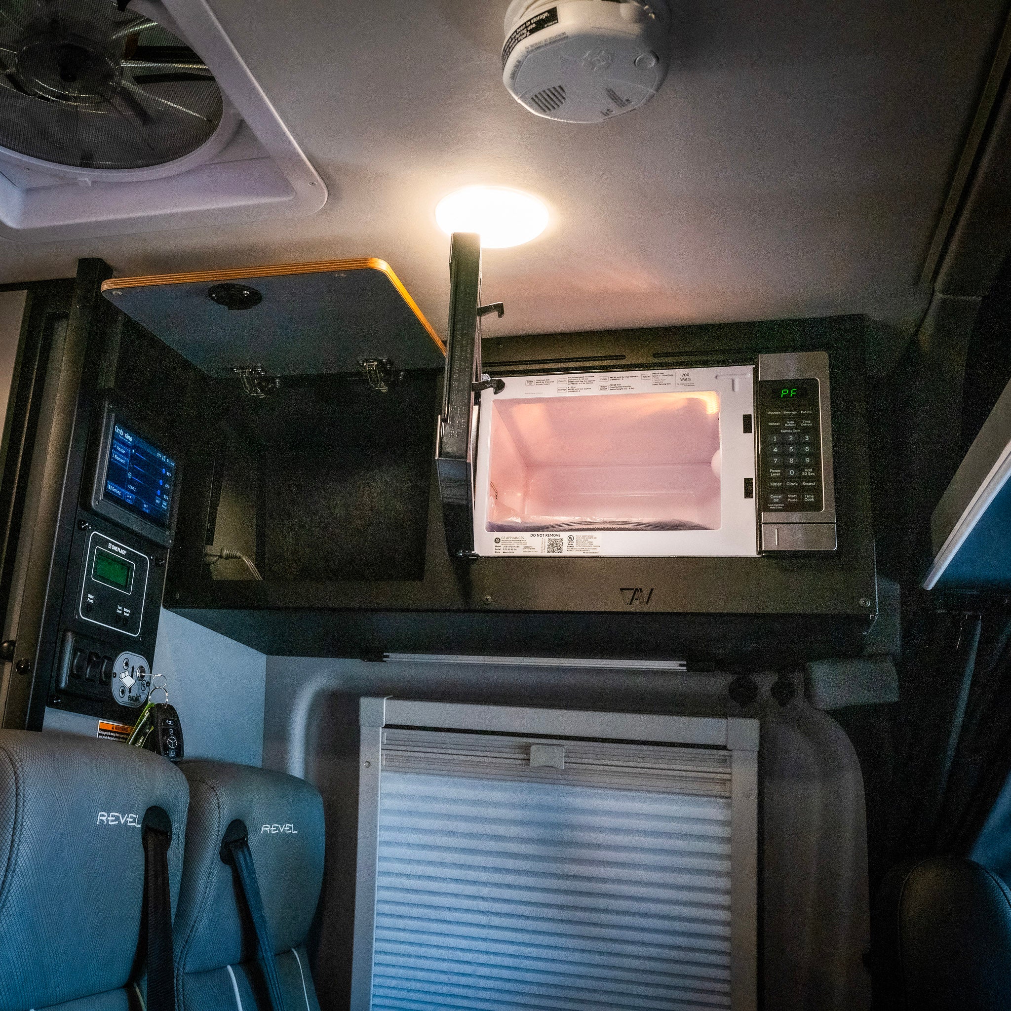 Revel overhead cabinet kit with microwave installed above van seating area.