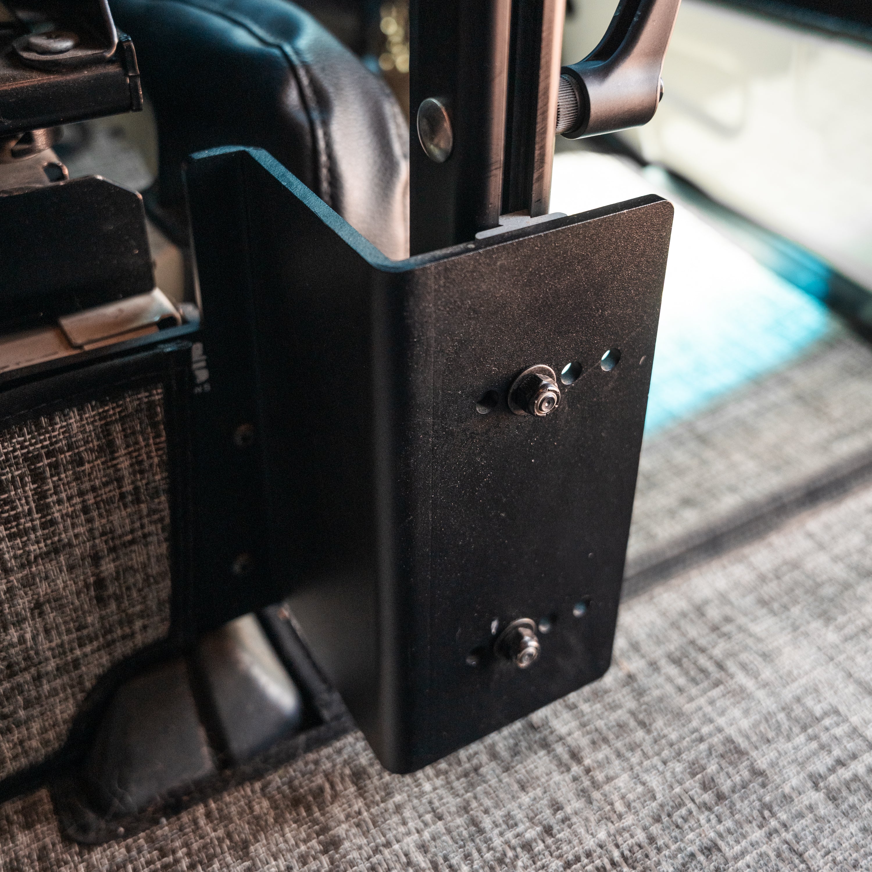 Close-up of a black metal console table bracket mounted inside a van near the drivers seat.