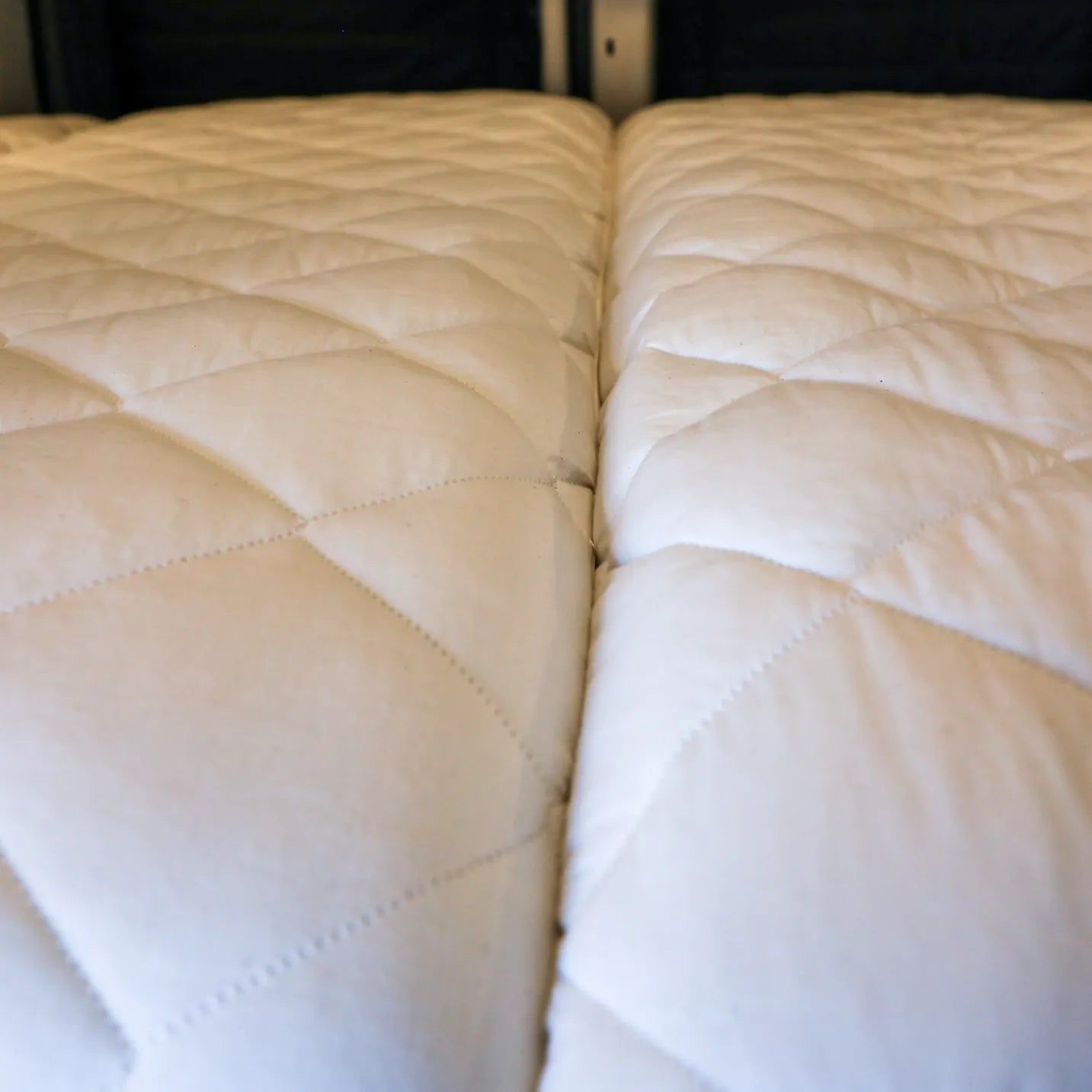 Close-up of quilted Dream Bundle mattress topper inside van with visible center seam.