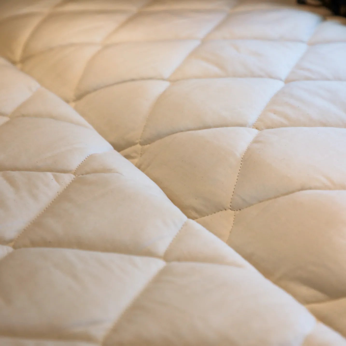 Quilted beige mattress topper from the Dream Bundle inside a van.