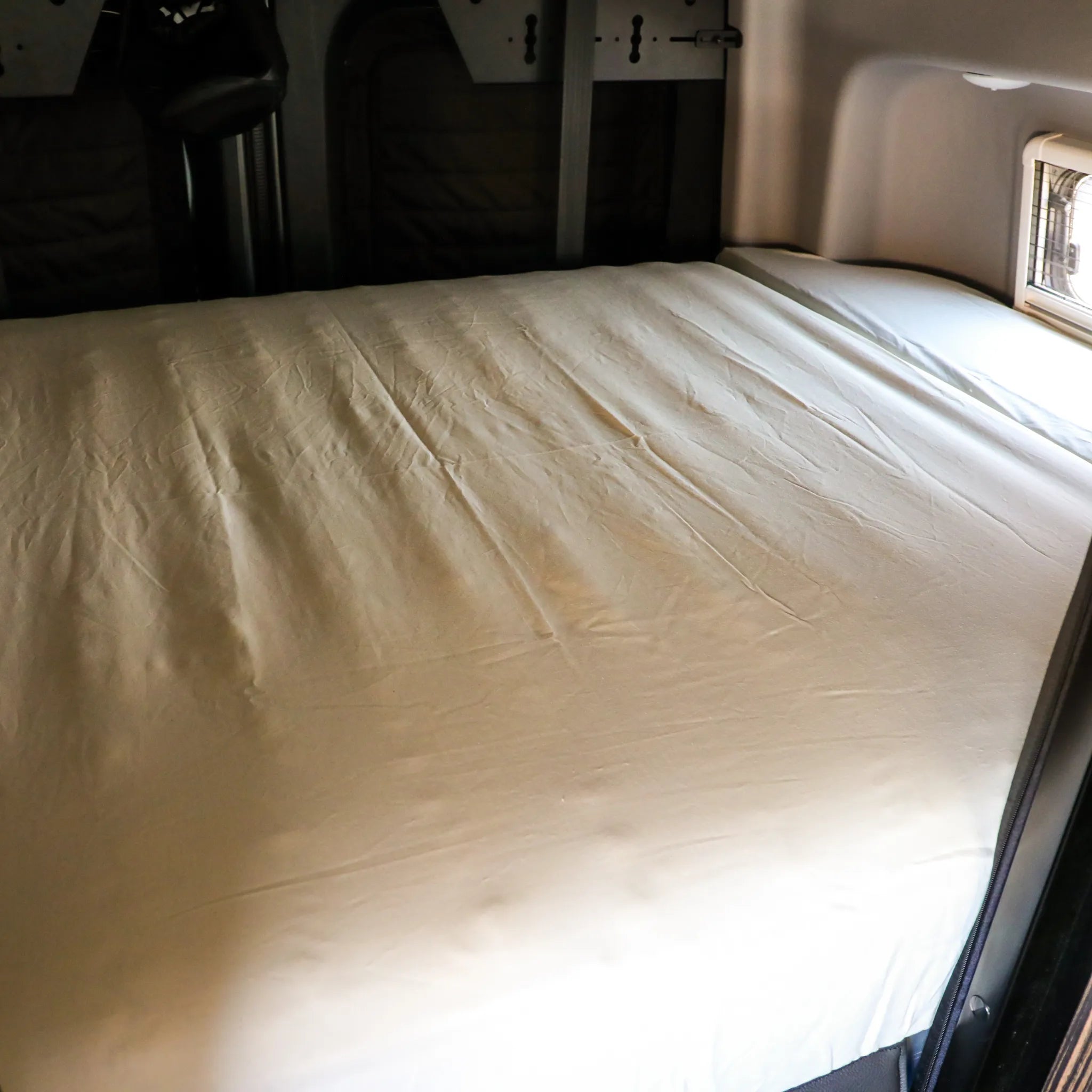 Dream Bundle mattress setup inside a Revel van, with window and interior walls visible.