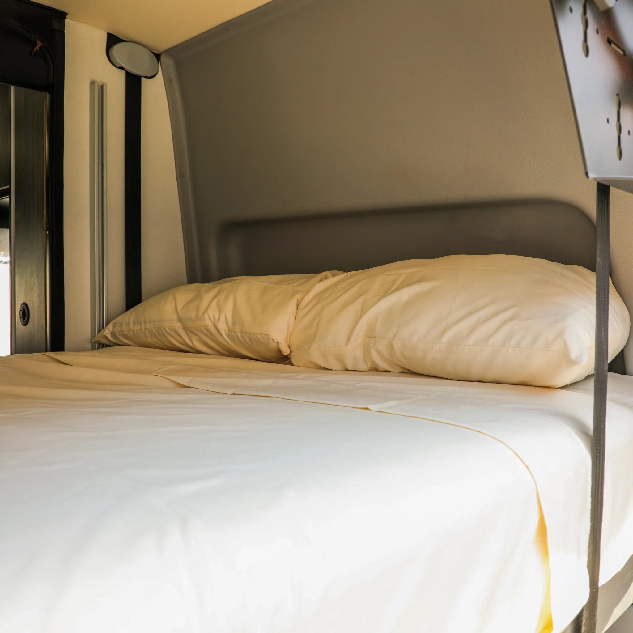 Cozy bed with cream bedding inside a Revel van from the Dream Bundle collection.