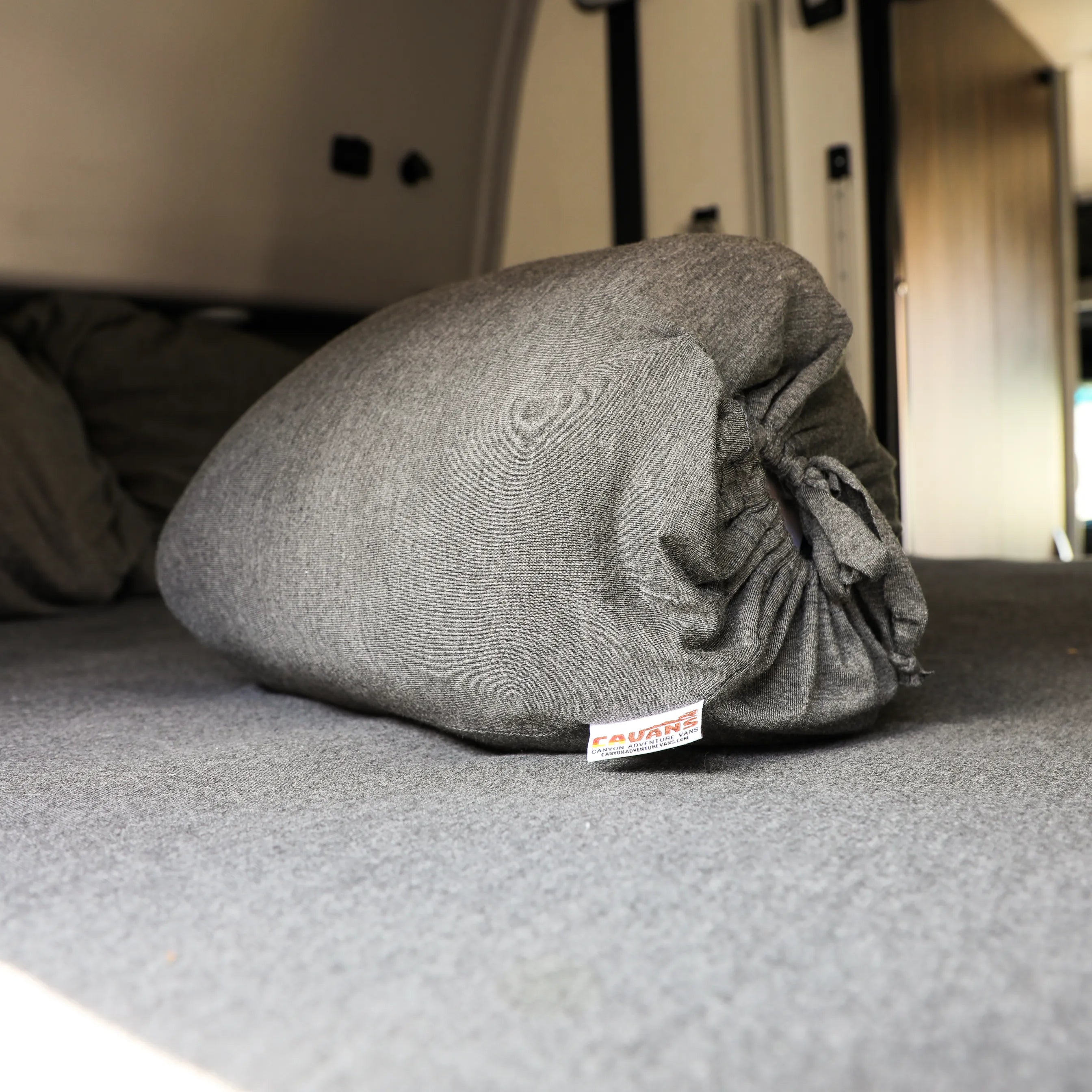 Rolled gray Classic Dream Sheet on bed inside van with Terrain tag visible