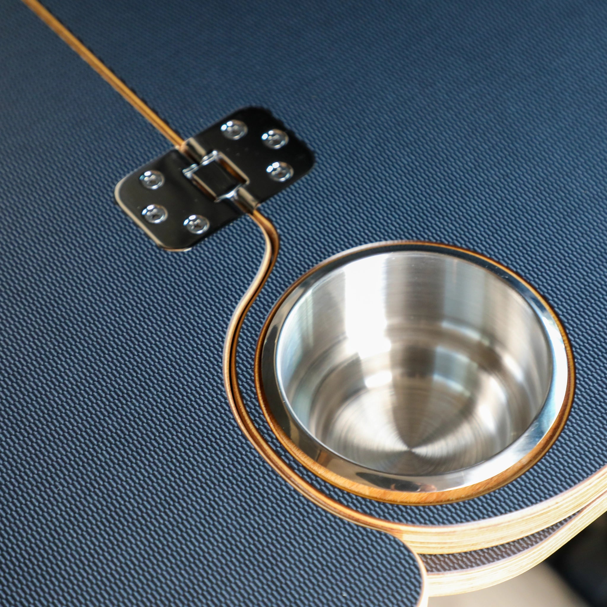 Close-up of Solo Folding Table Top with built-in metal cup holder on textured surface.
