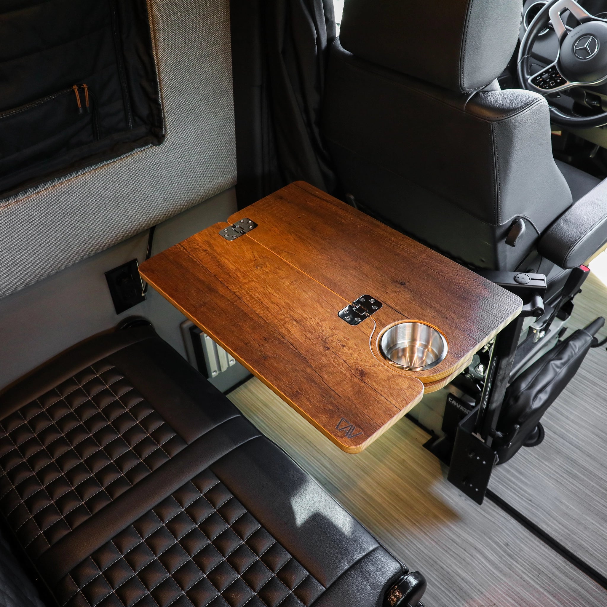 Solo Folding Table Top mounted in a van between black seat and driver area with built-in cup holder