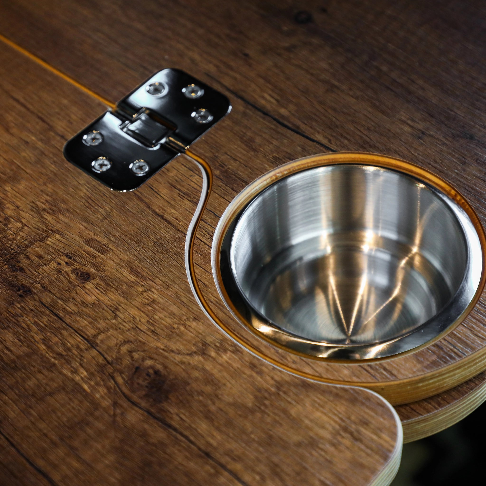 Close-up of Solo Folding Table Top with wood finish and built-in metal cup holder in a van.