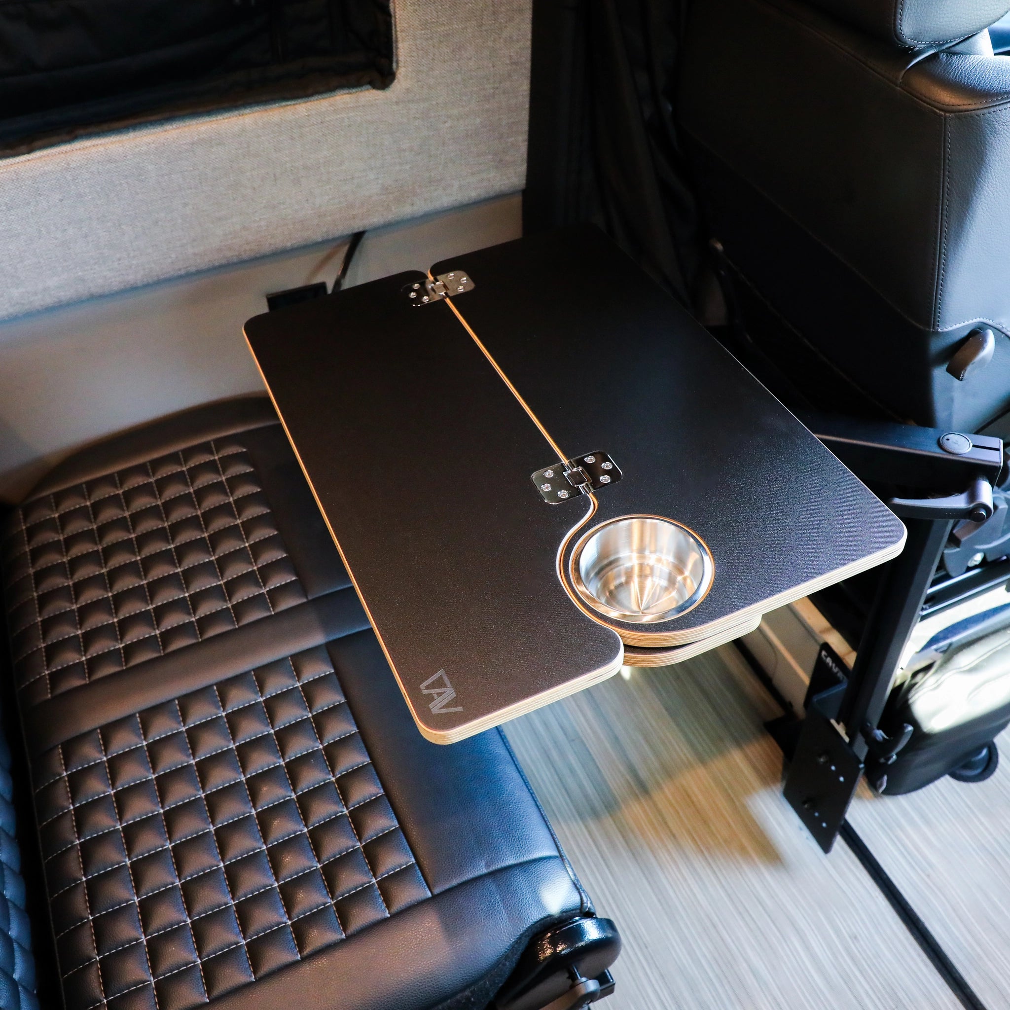 Fold-out Revel table with cup holder mounted between black leather van seats