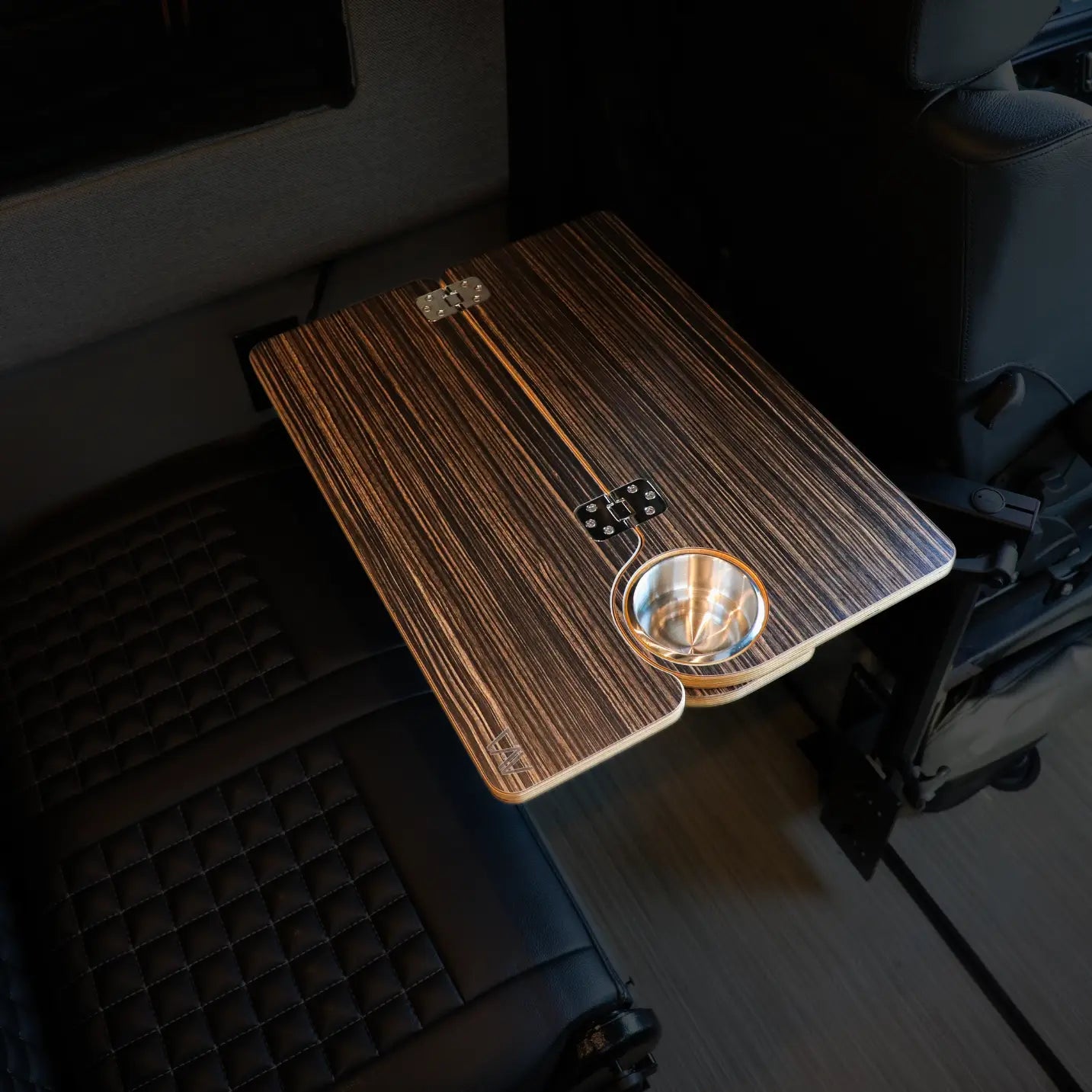 Solo Folding Table Top by CAV mounted between van seats with integrated cup holder and woodgrain finish.