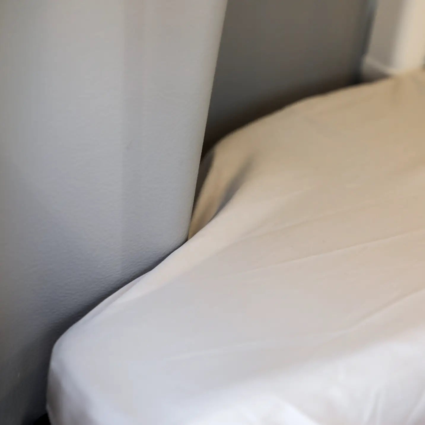 Close-up of a fitted sheet covering a mattress corner inside a van.