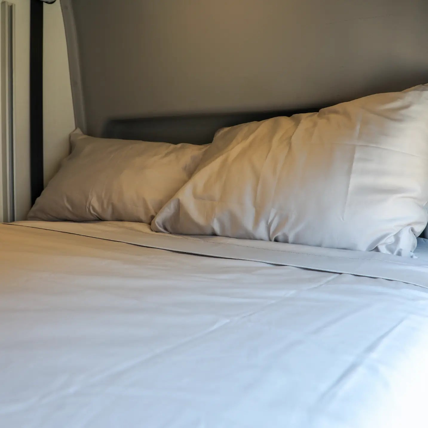 Ultra Luxe Dream Sheets by Revel neatly arranged on a van bed with two pillows.