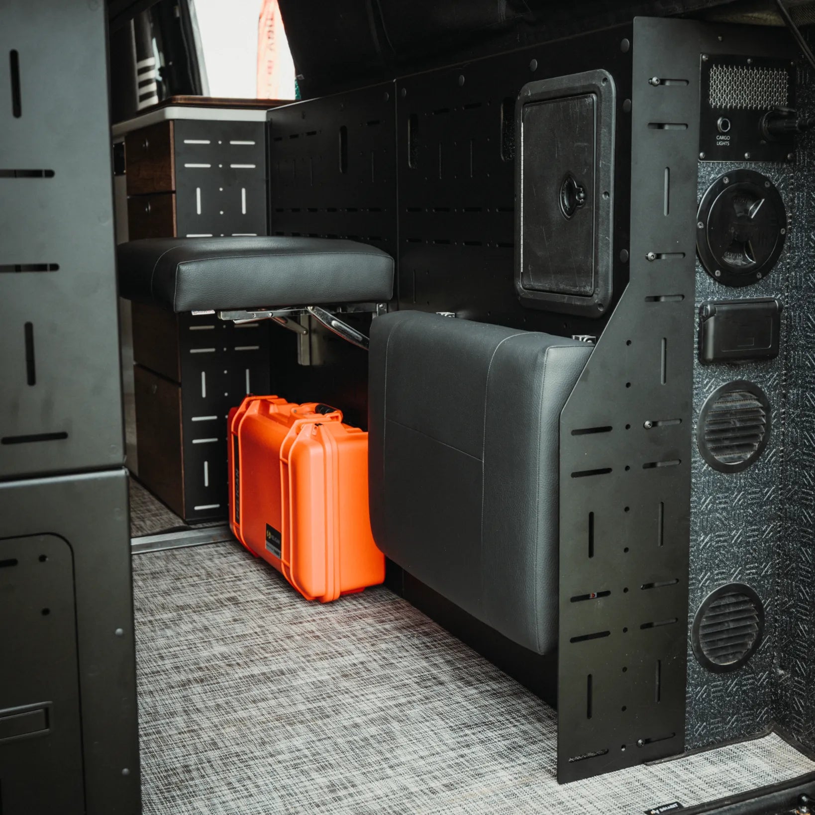 Passenger Gear Wall Pro by Storyteller Overland installed in van with fold-down seats and storage space.
