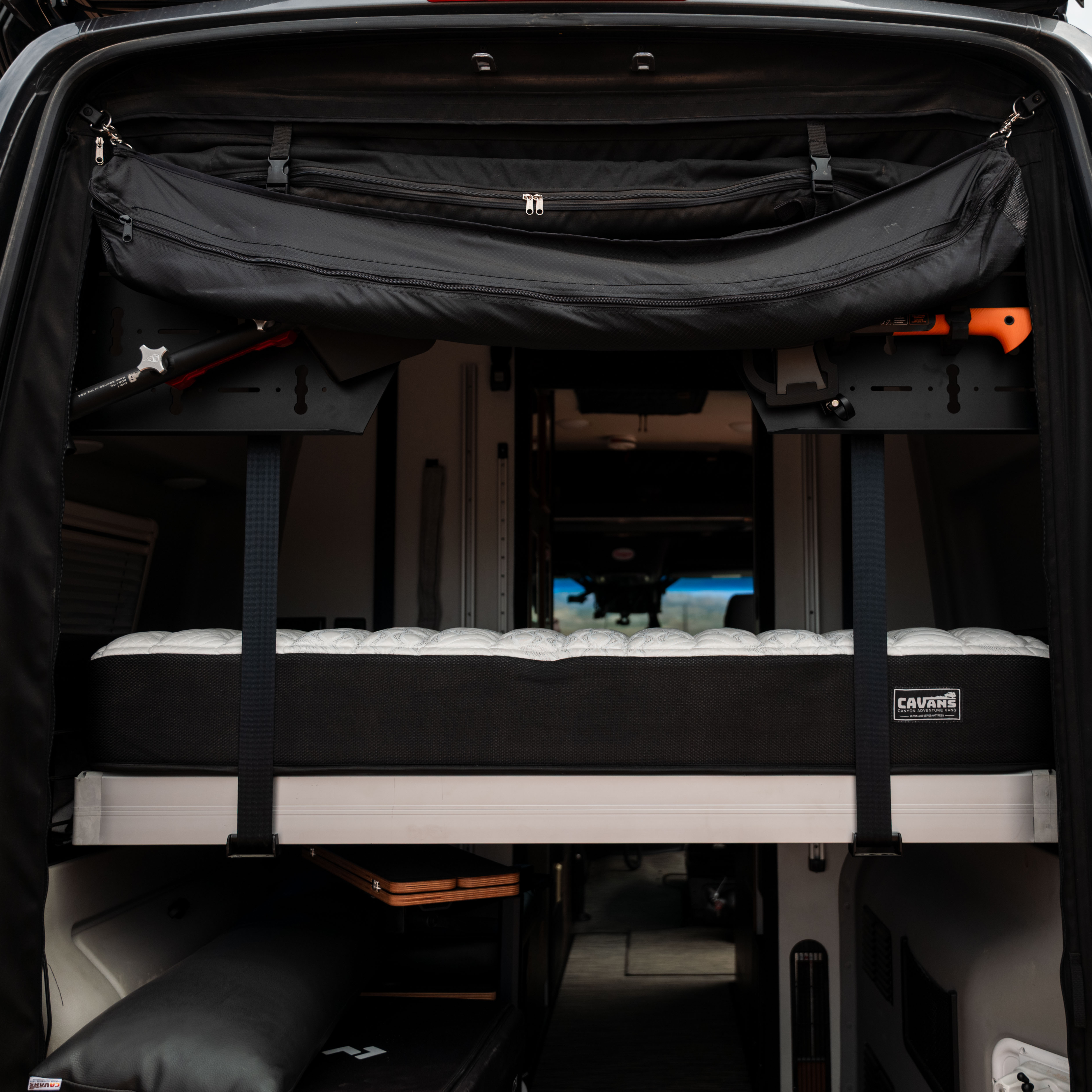 CAV Ultra Luxe mattress setup inside a Revel van with fold-out bed platform and gear storage.