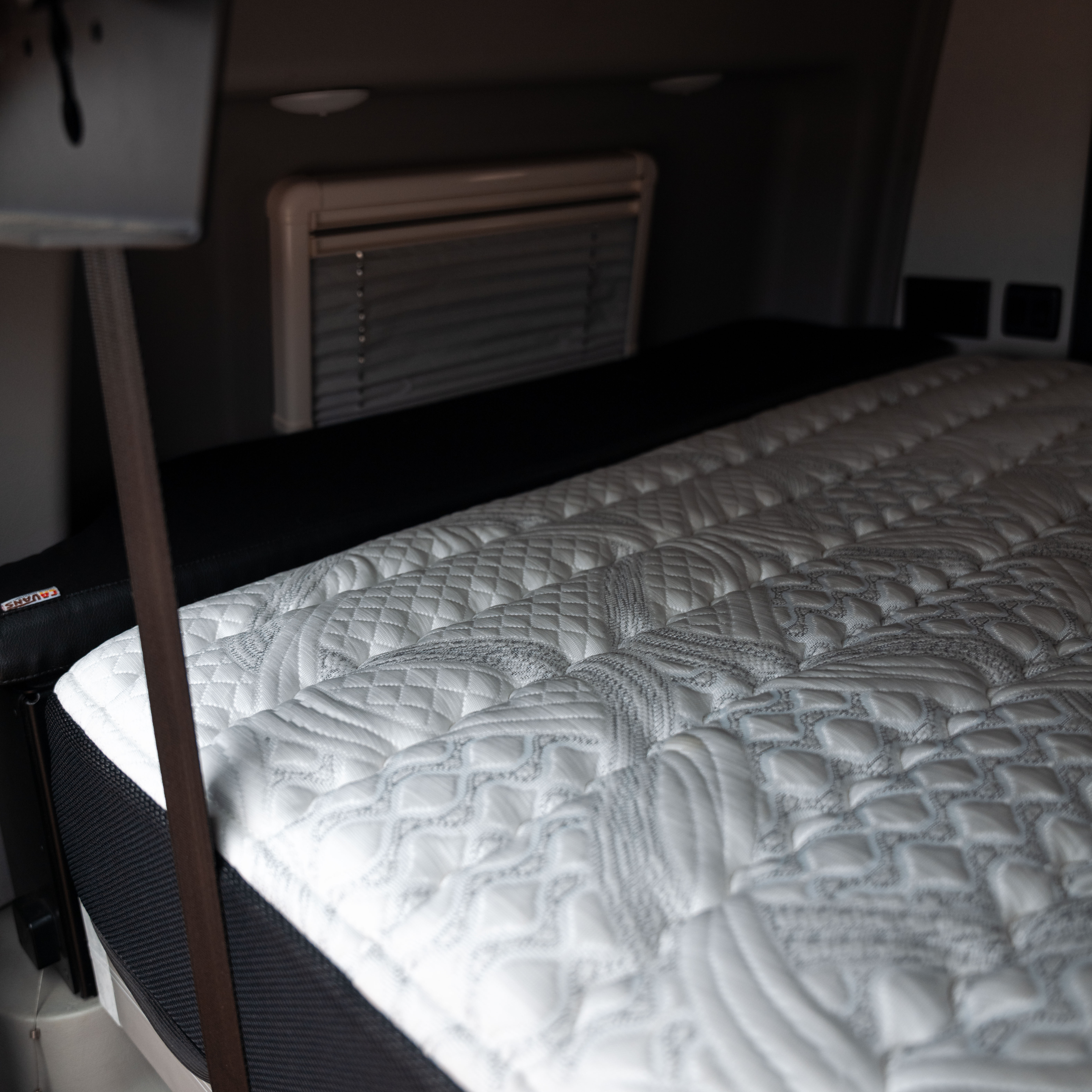 Close-up of ULTRA Luxe Mattress in a Terrain van with quilted detailing and black base.