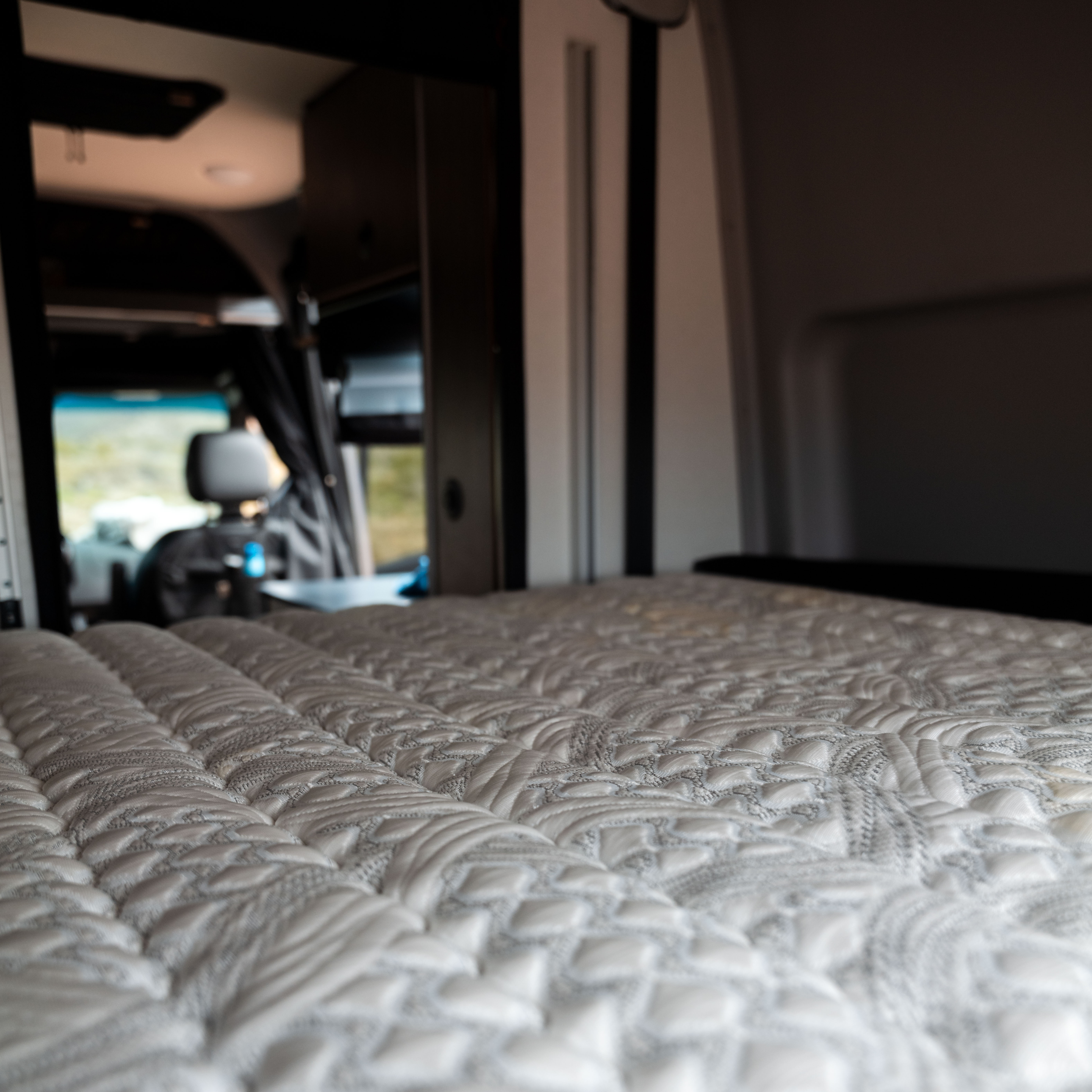 Close-up of ULTRA Luxe mattress inside a van with view toward the front cabin