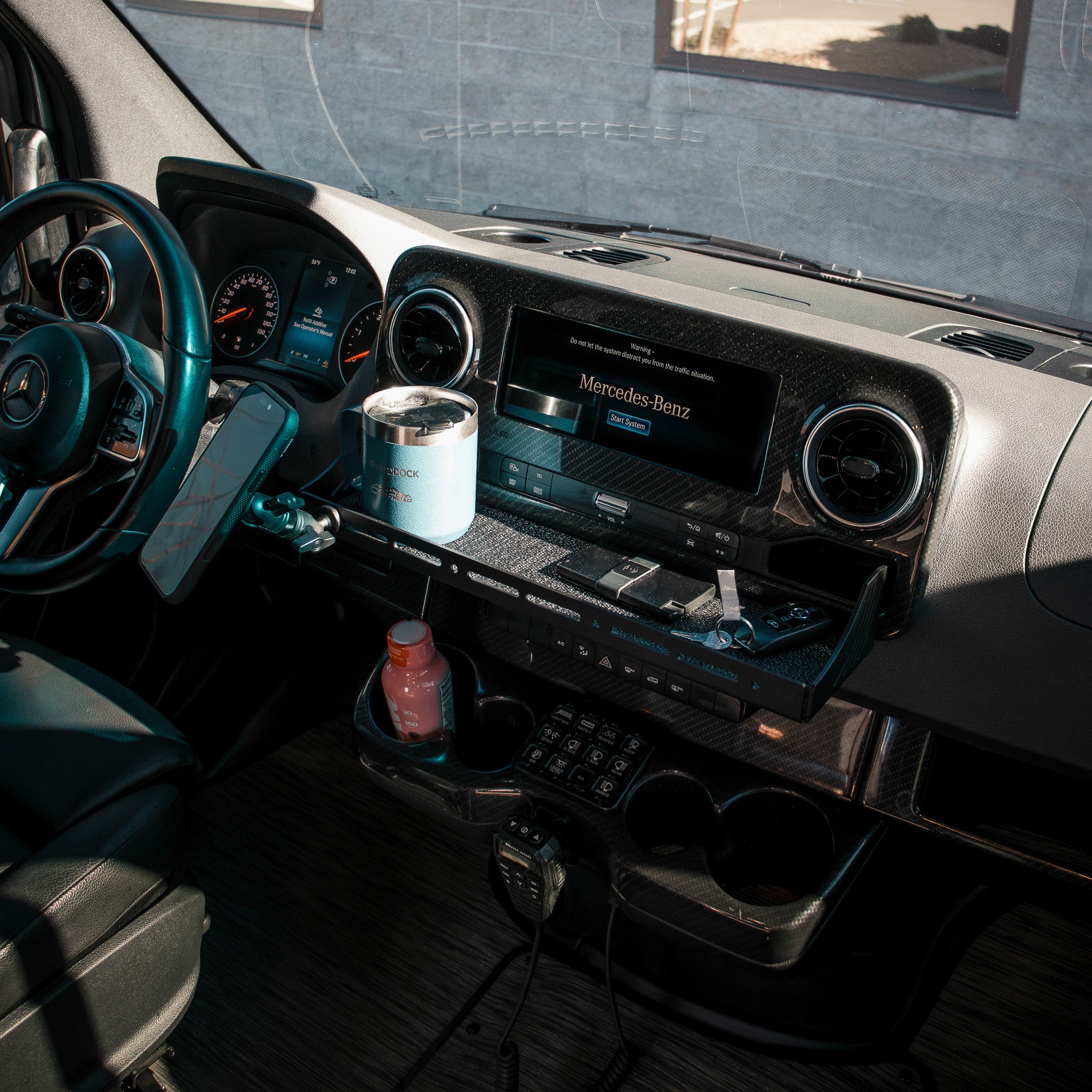 CAV Dash Tray Pro shown installed on a mercedes sprinter van dashboard holding keys wallet and drink tumbler with bulletpoint magsafe mount and phone attached by carbon fiber kevlar mount arm and female ball mounting adapter