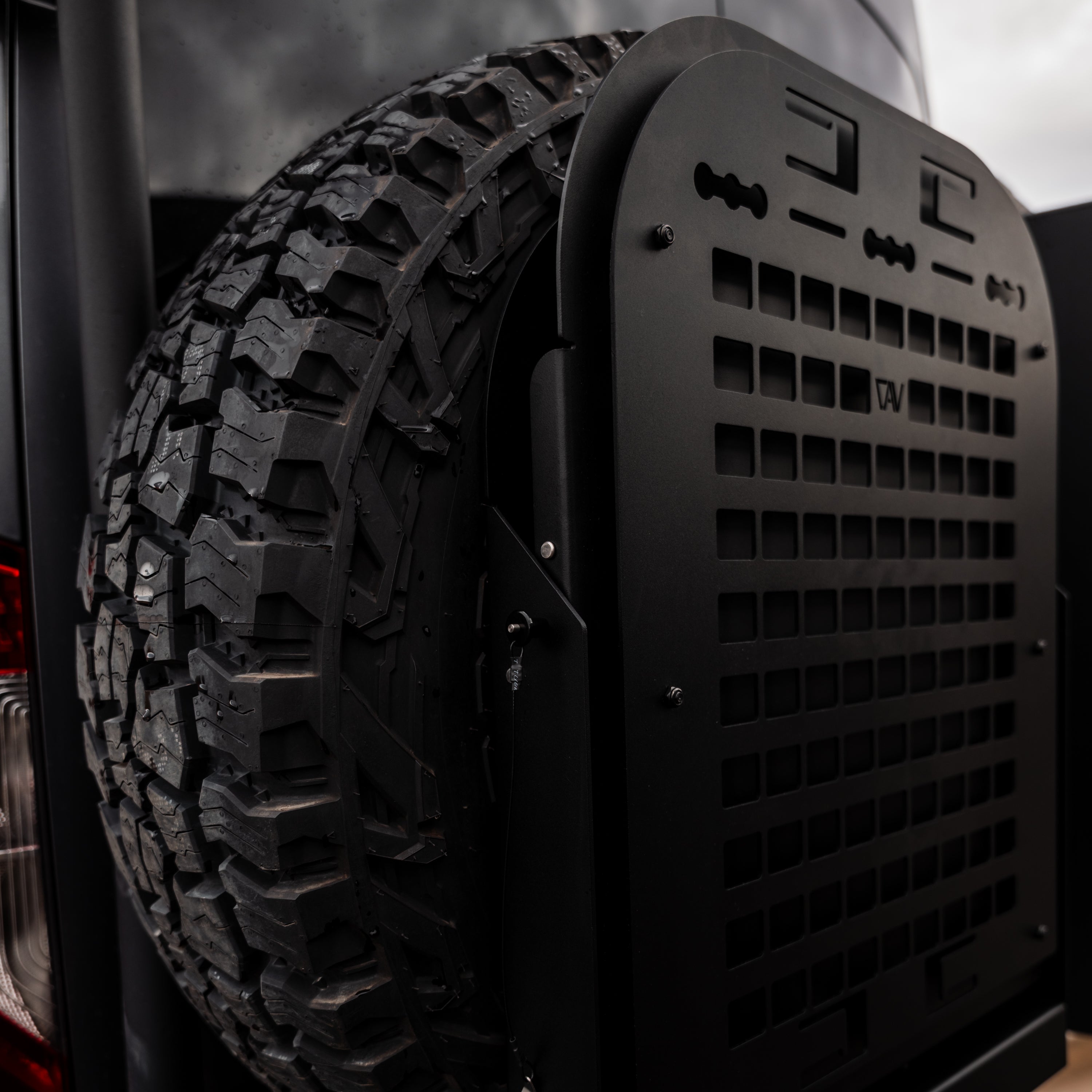 Canyon Tire Carrier Drop Table mounted beside spare tire on back of van.