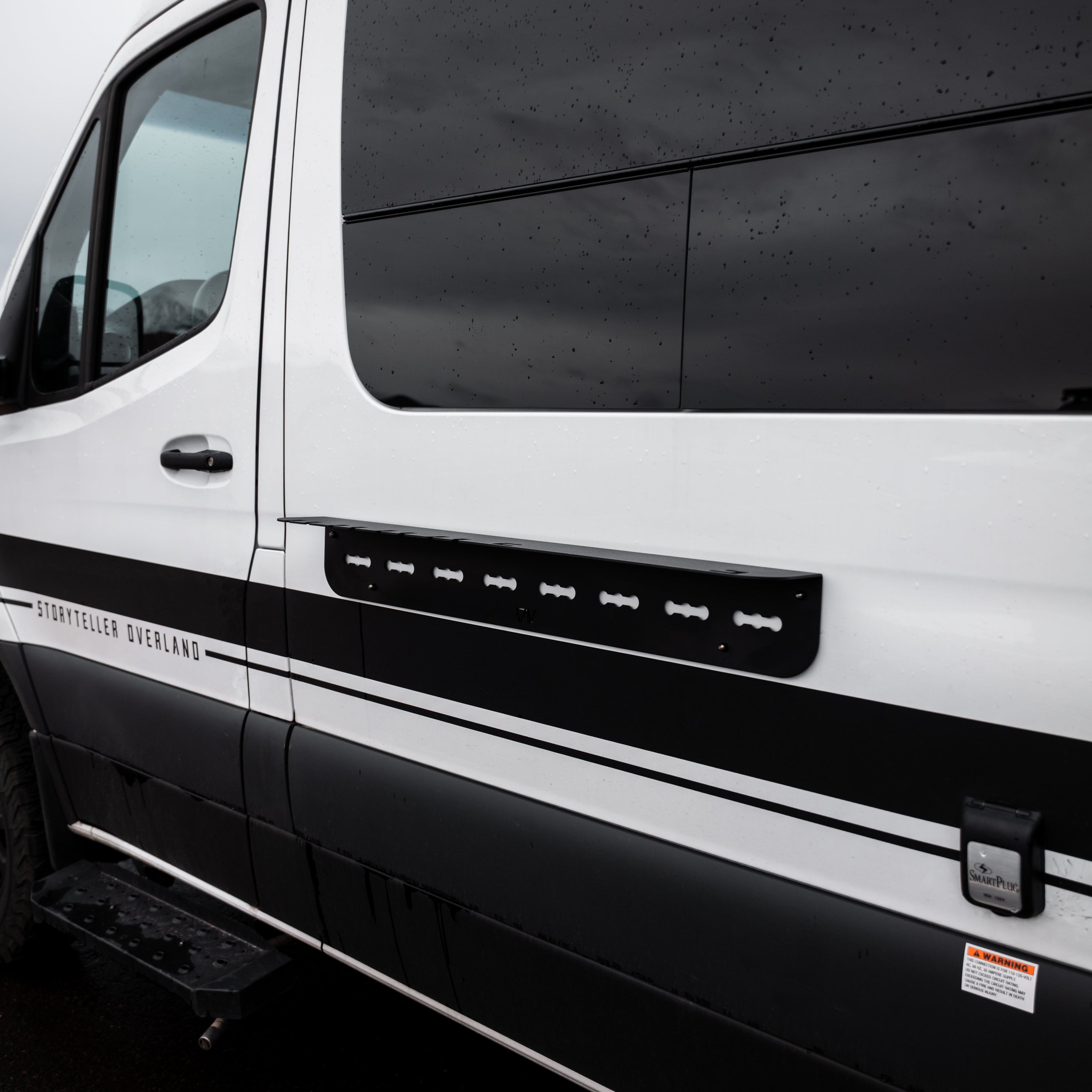 Storyteller van with mounted black outdoor utility shelf on side panel