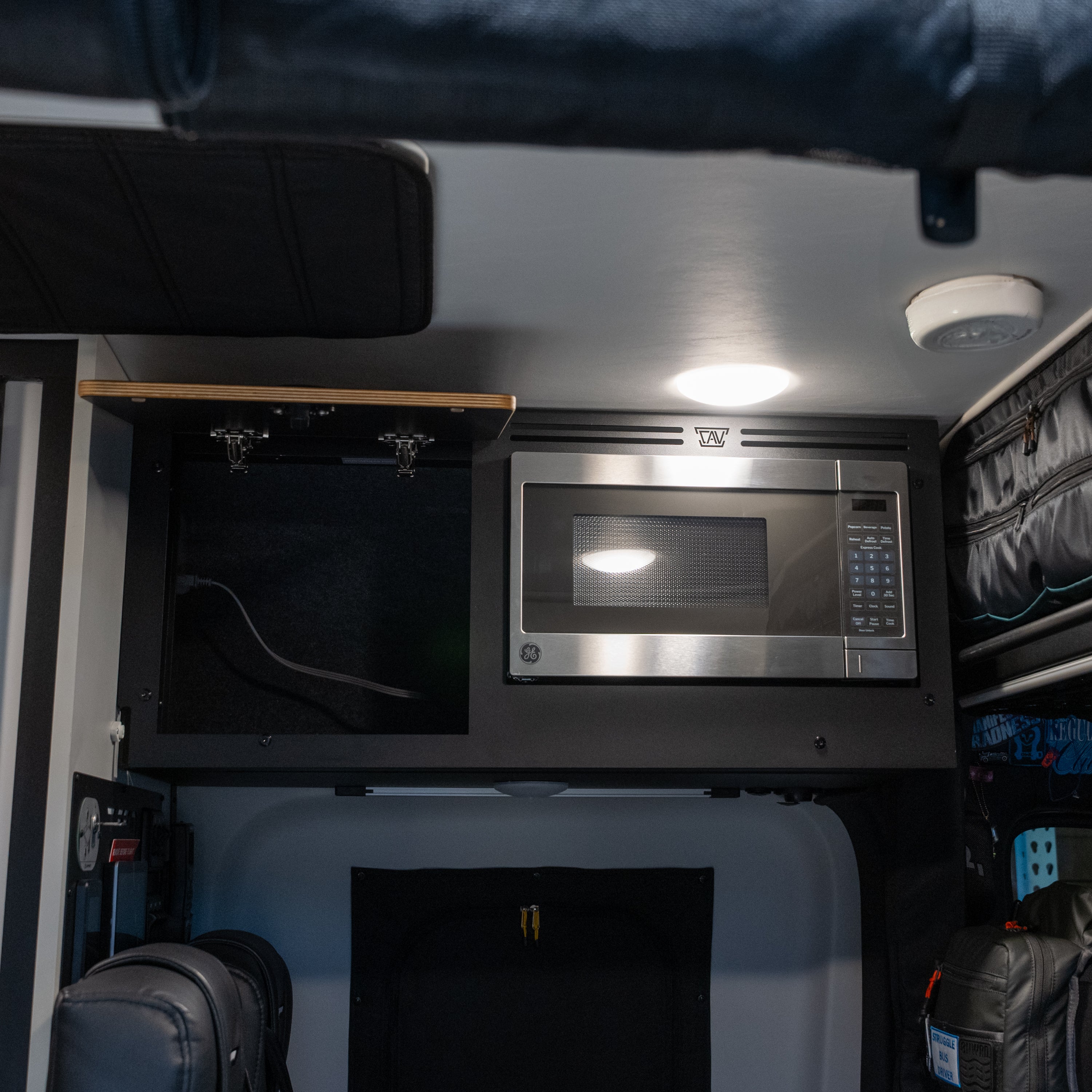 Tiffin GH1 Microwave Kit installed above storage cabinet in van interior.