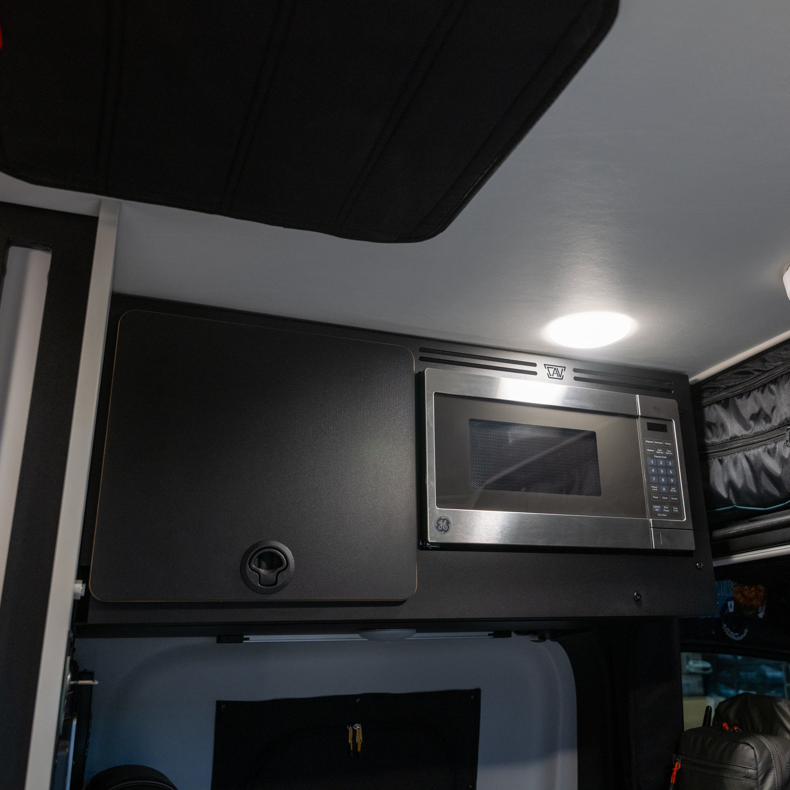 Tiffin GH1 microwave kit installed in upper van cabinet with overhead lighting