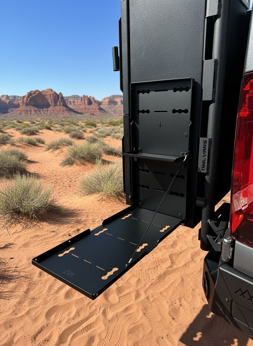 Canyon Drop Down Table by Owl Vans mounted on the rear door of a van in a desert landscape
