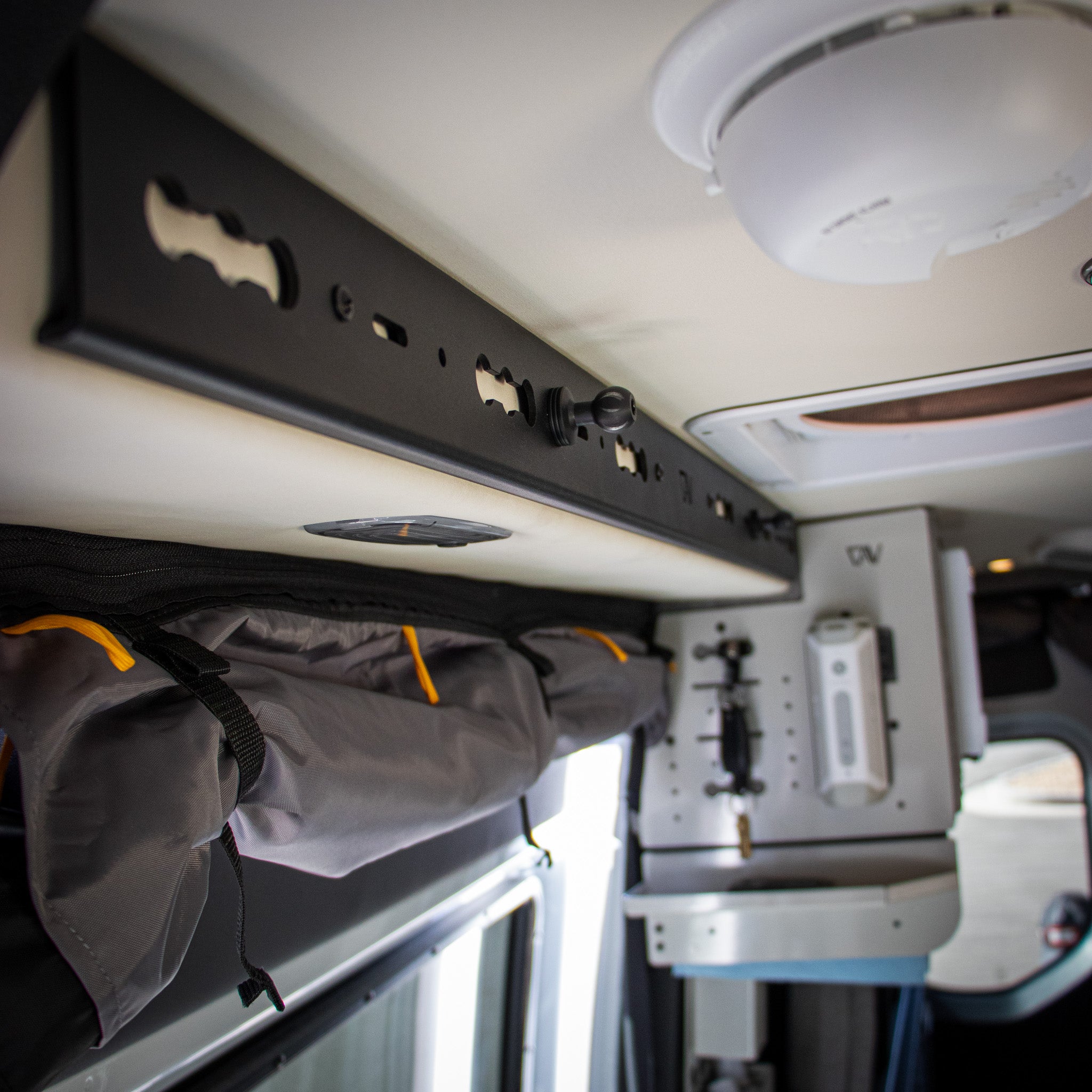 interior. ofstoryteller overland mode closeup of black l track pro mounted above sliding door and ball mounts screwed in.