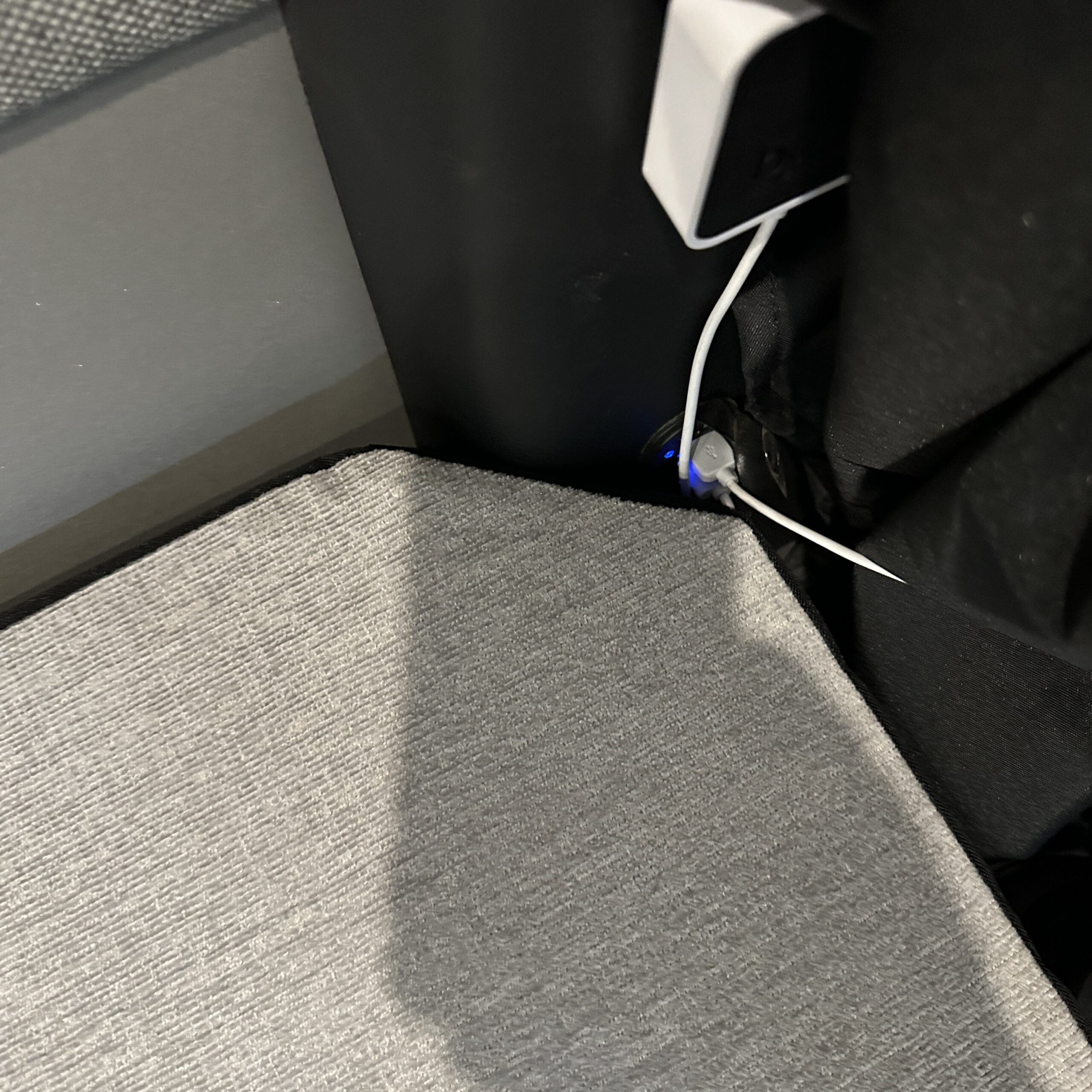Corner view of Groove Lounge Mattress Topper fitted in a van interior near power outlet.