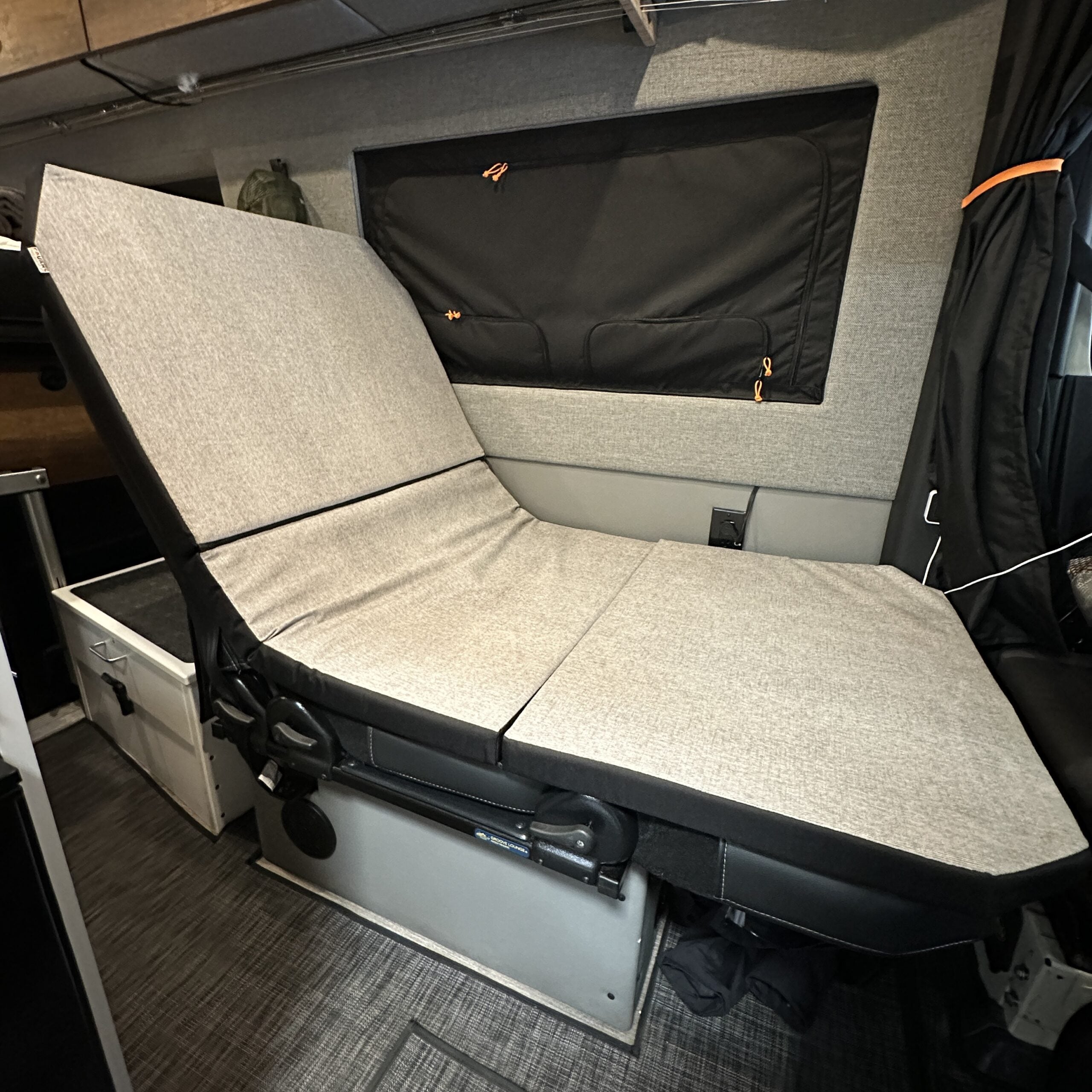 Groove Lounge Mattress Topper in a Storyteller van shown in reclined position with grey upholstery.