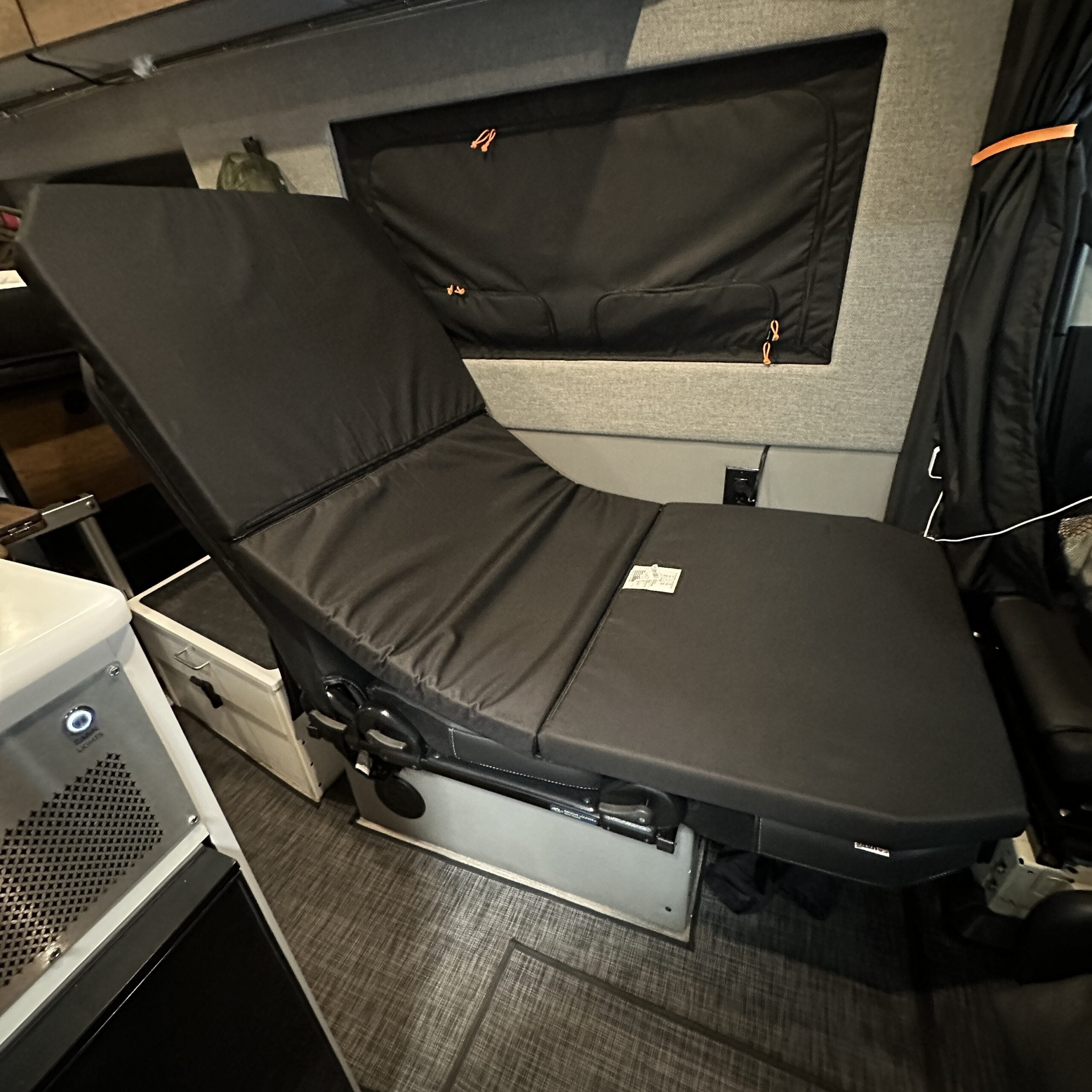 Groove Lounge Mattress Topper by Revel shown on reclining seat setup inside a Storyteller van interior.