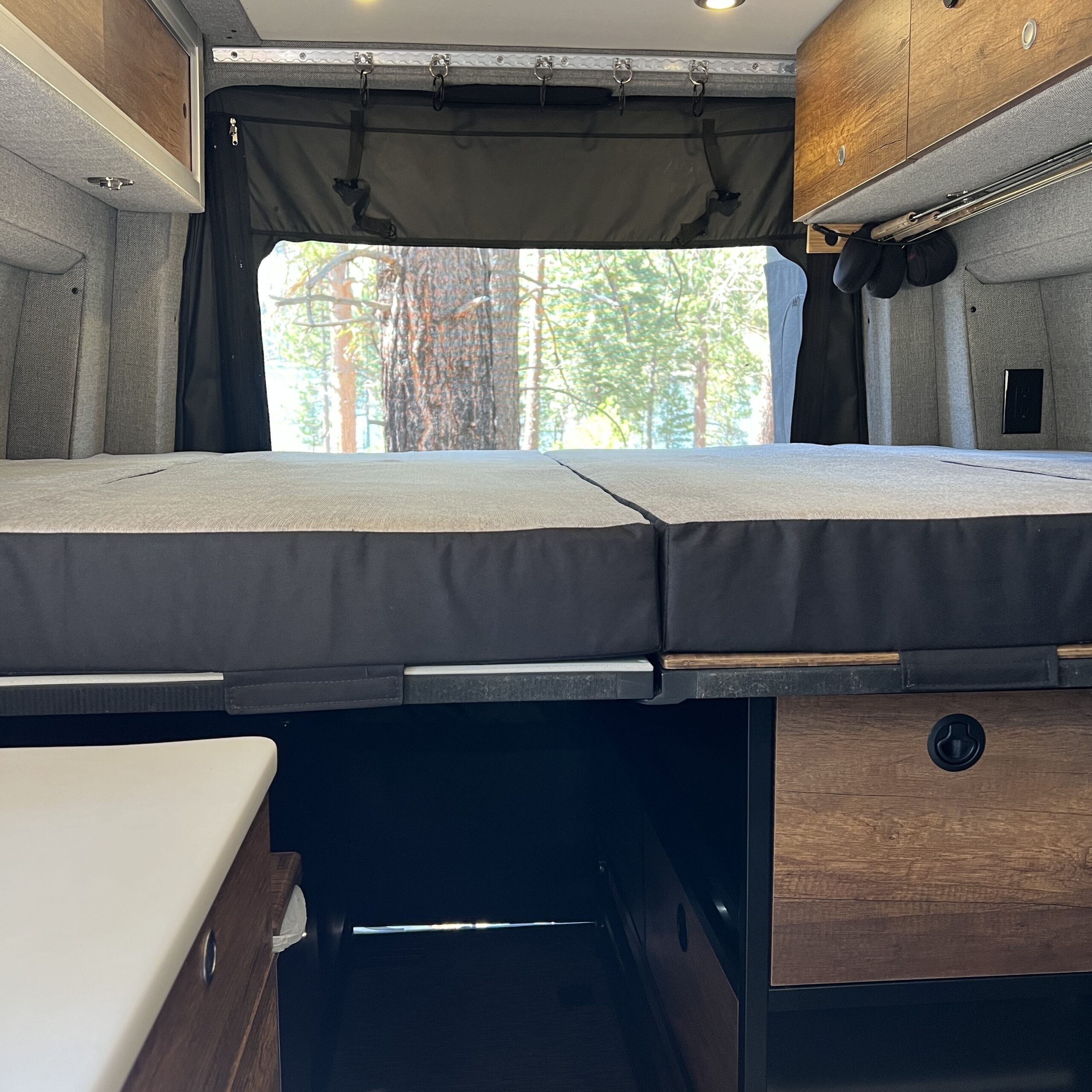 Luxe5 semi firm cooling memory foam mattress set up in a Storyteller MODE van interior with wood cabinetry.