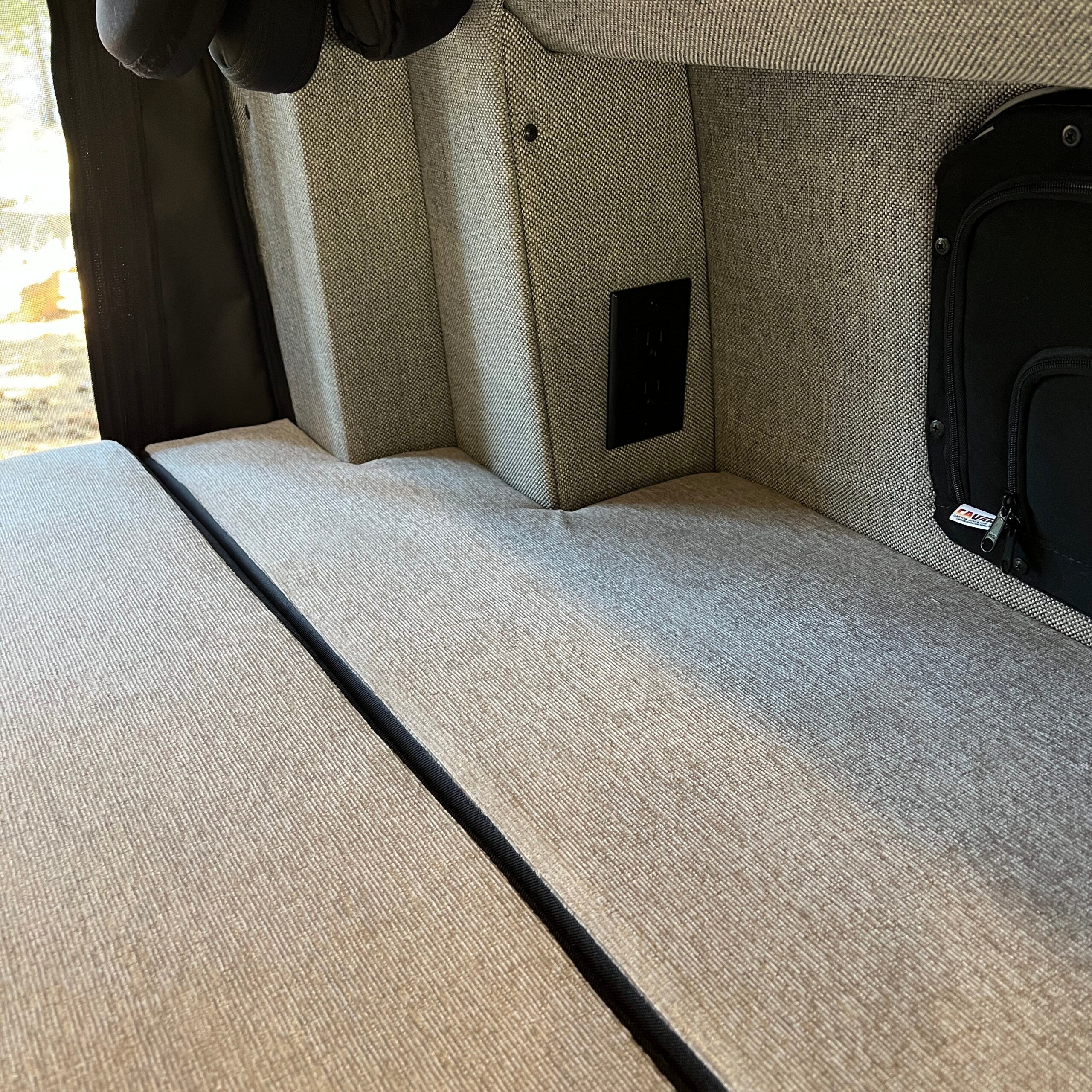 Revel Luxe5 cooling memory foam mattress in a Storyteller MODE van interior with outlet panel visible